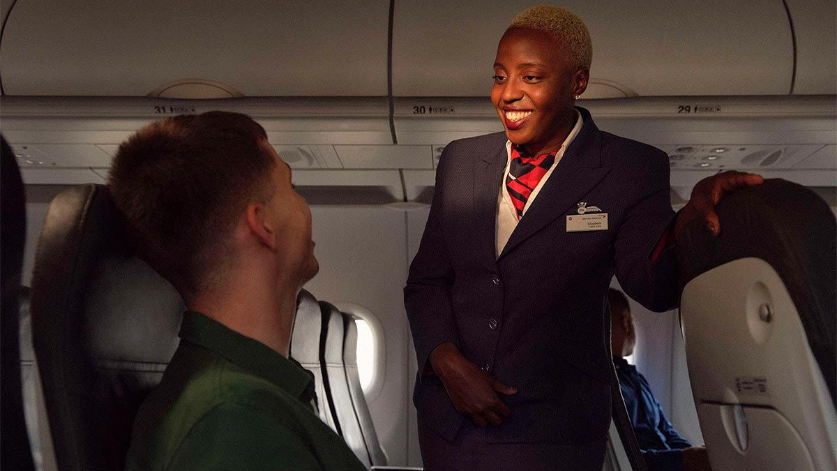 A flight attendant and passenger chatting onboard a British Airways aircraft.