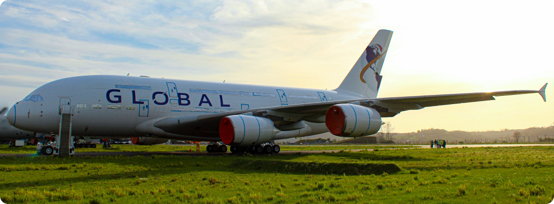A Global Airlines Airbus A380 parked at a field.