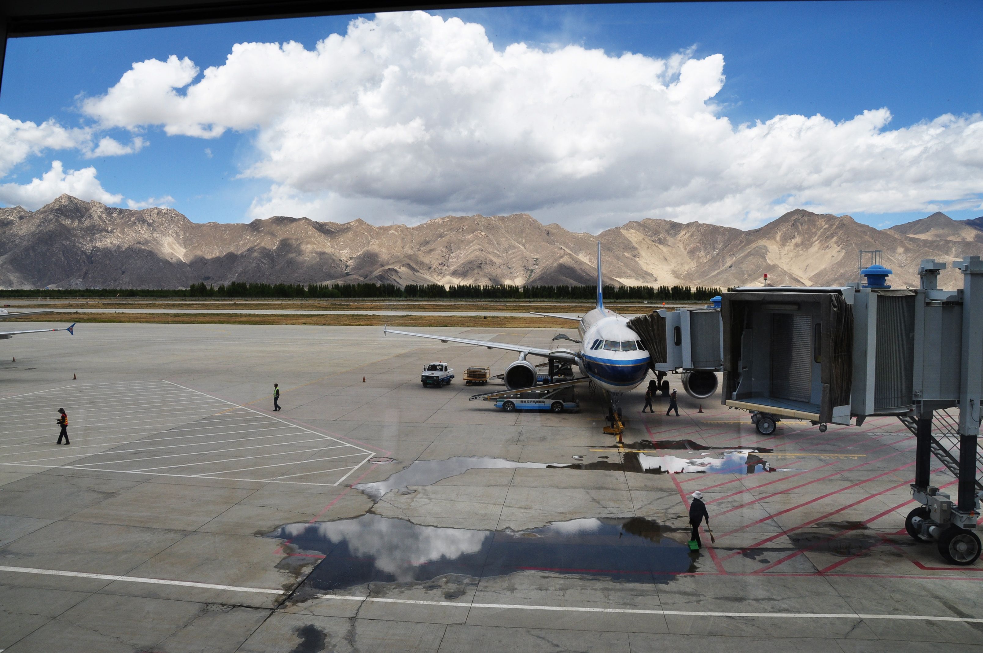 An aircraft parked at Lhasa airport, with mountains in the background.