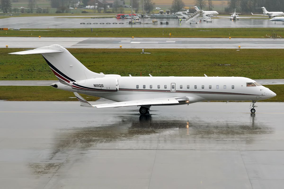 A Bombardier Global 5000 taxiing to the runway on a rainy day.