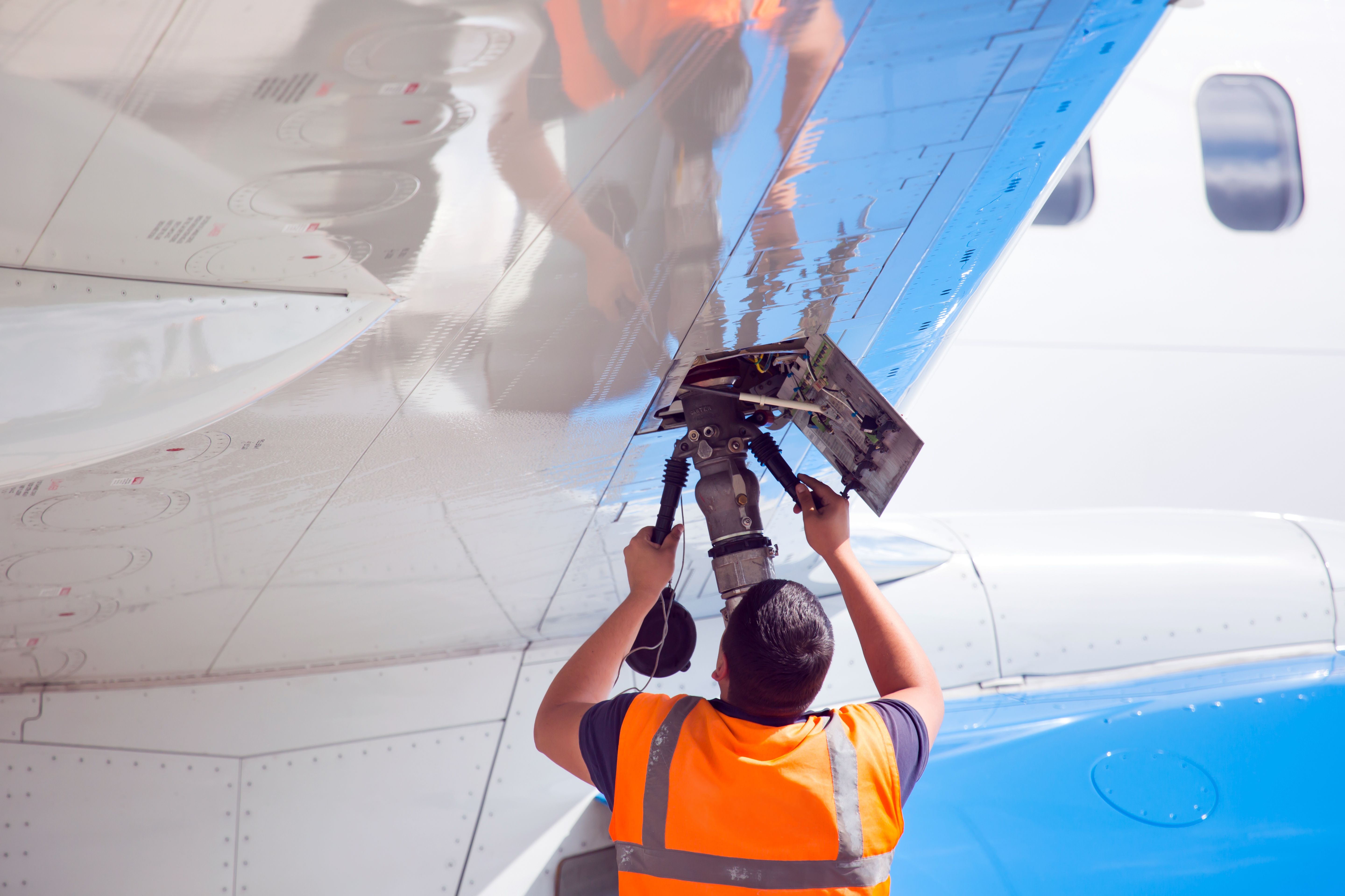 A ground crew worker refuelling an aircraft.