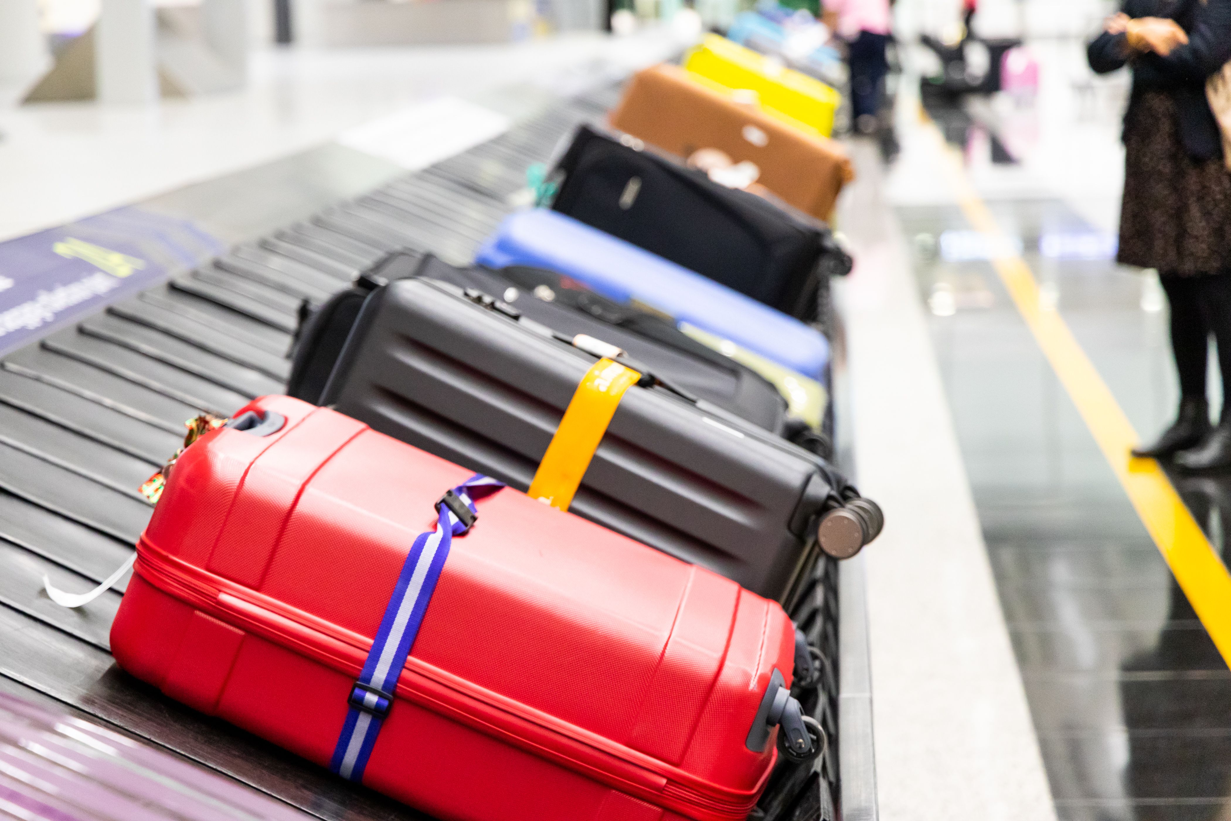 Passengers stand around a luggage carousel with many bags.