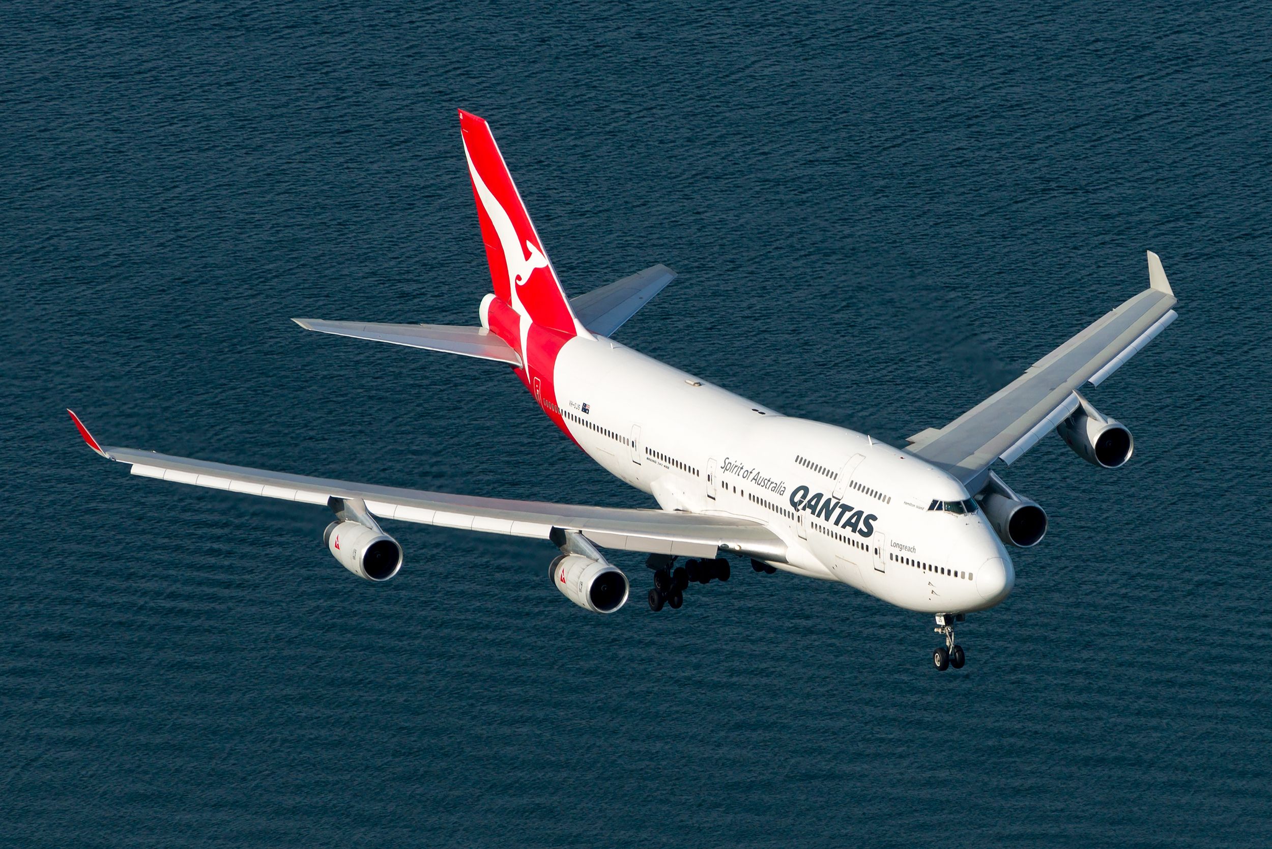 A Qantas Boeing 747-400 flying over water.