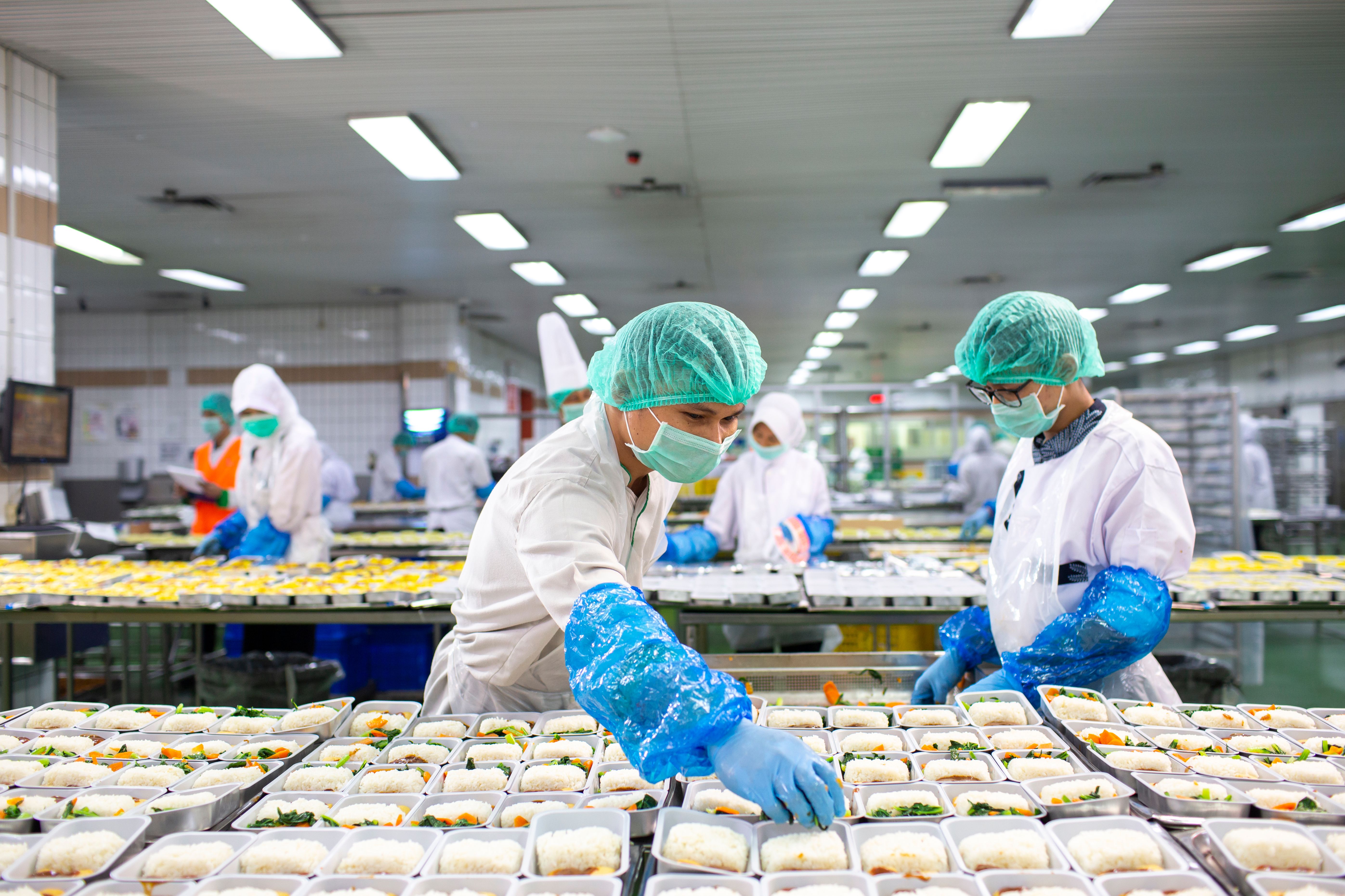 Workers in a caterering facility preparing in-flight meals.