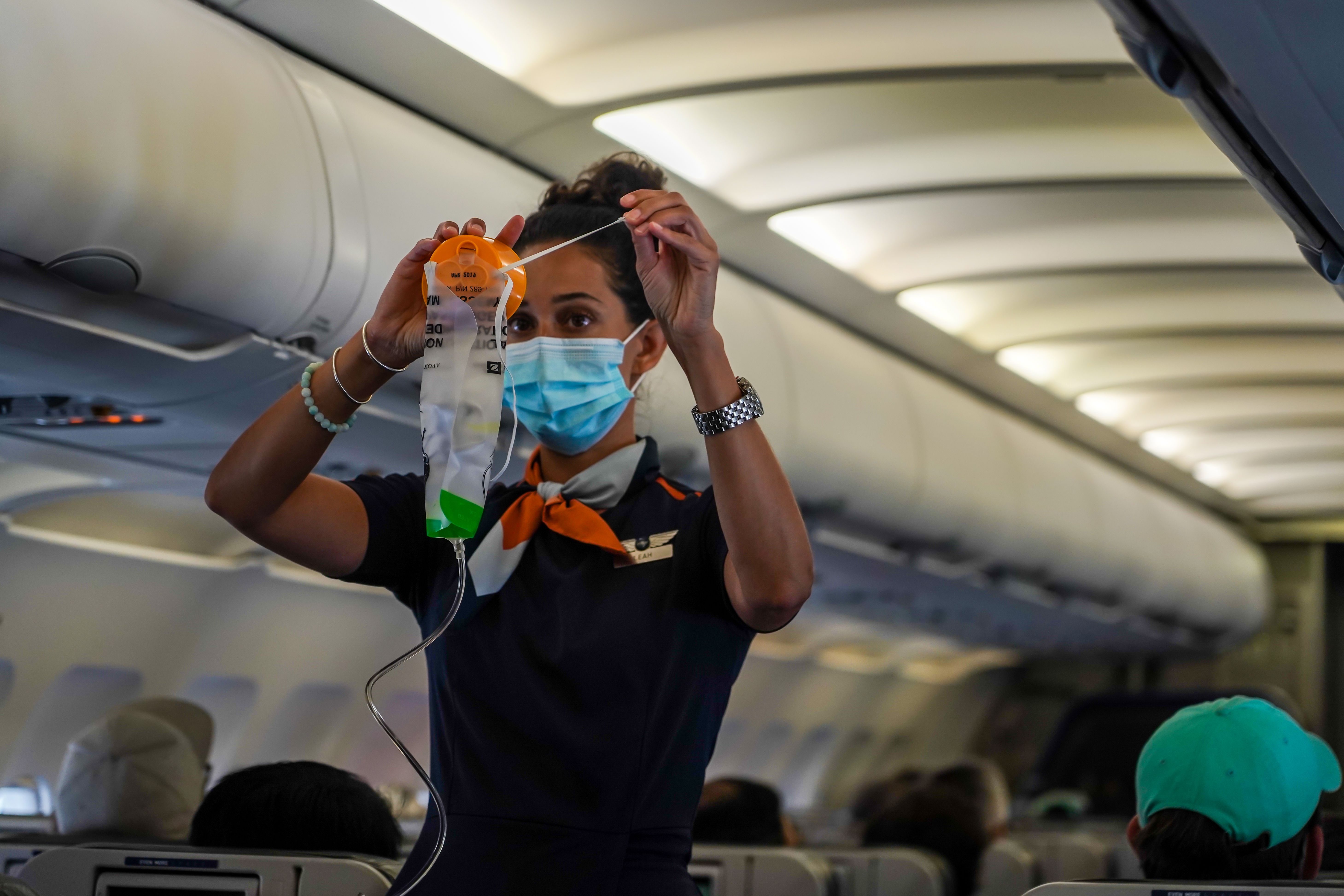 A flight attendant demonstrating how to use an oxygen mask.