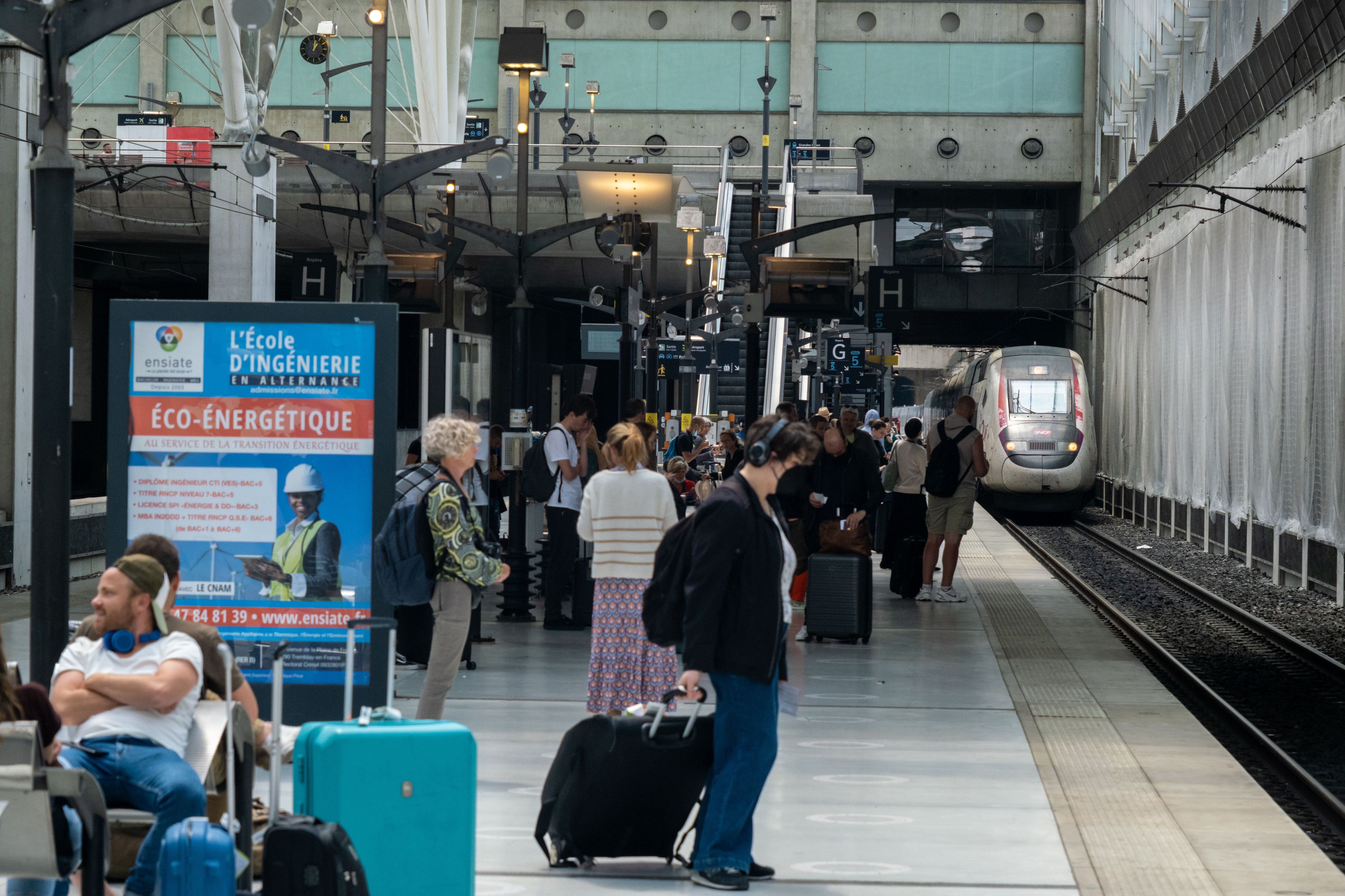Several passengers waiting at the Paris CDG Airport train station.
