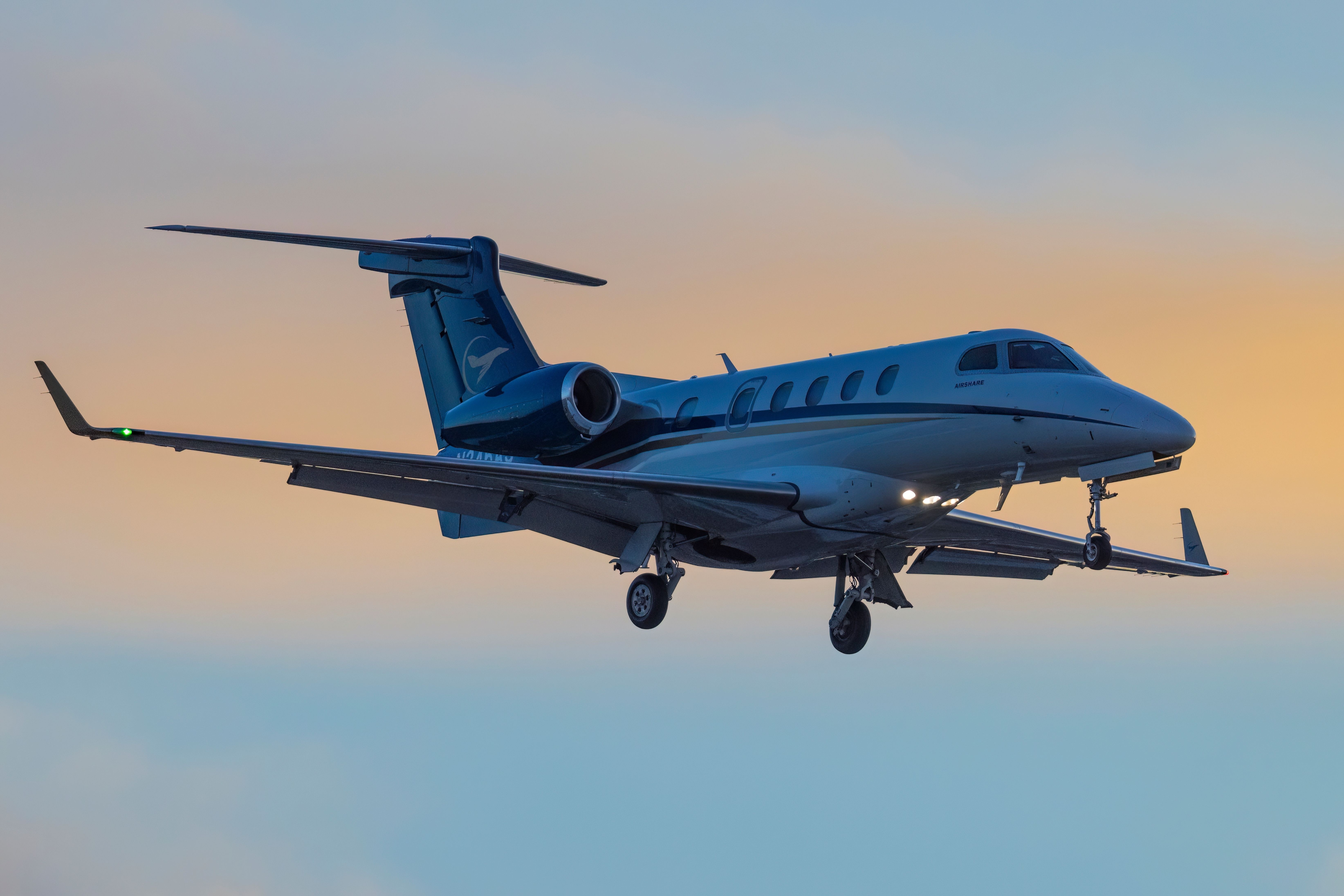 An Embraer Phenom 300 on final approach during sunset.