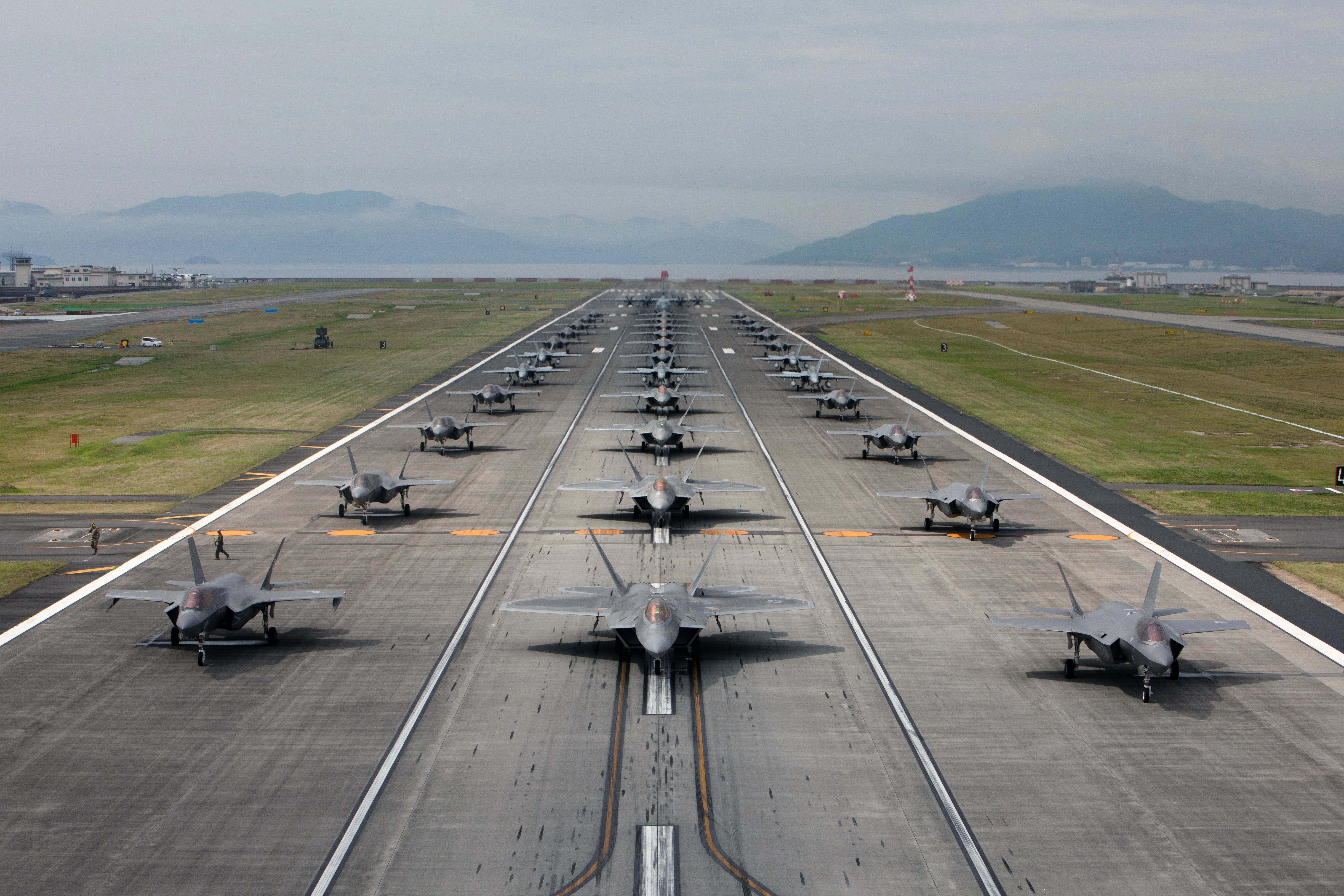 Dozens of F-22 Raptors lined up on a runway.