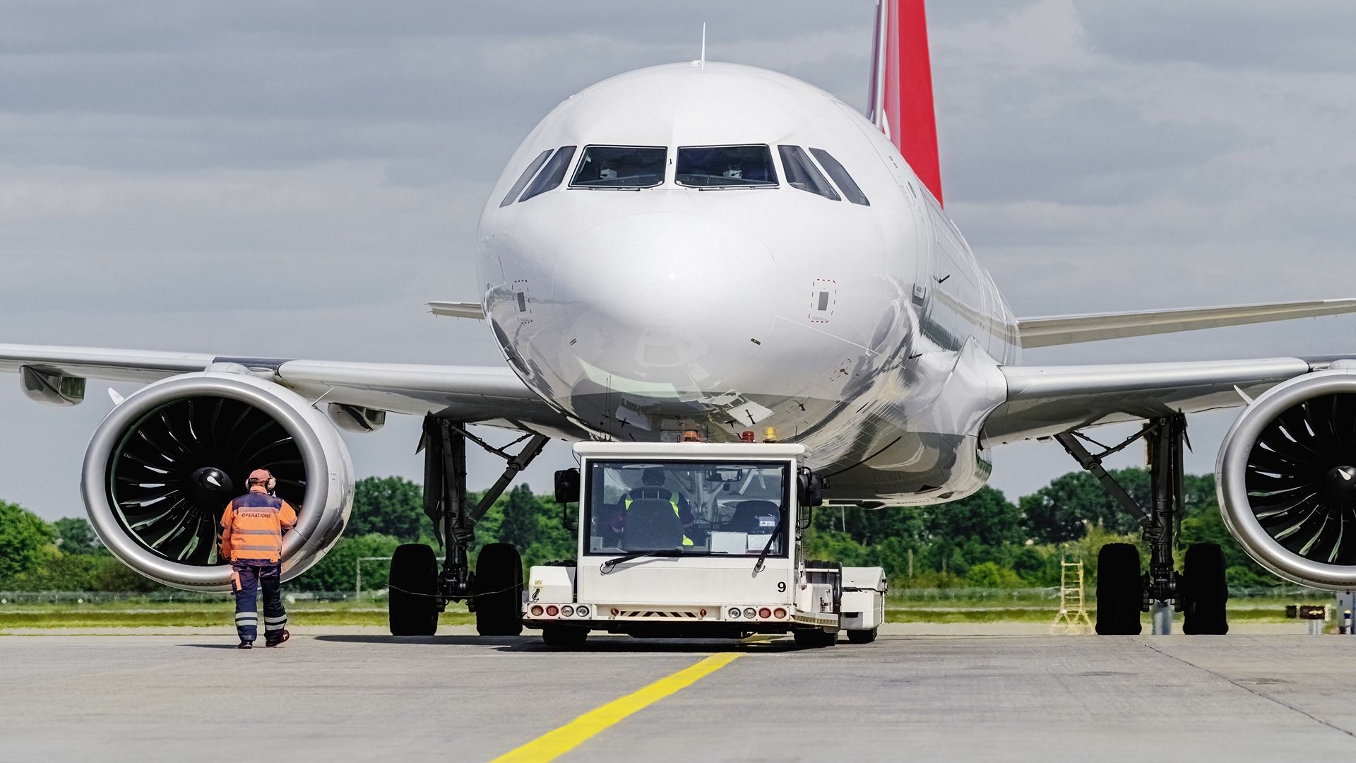 A ground operator can be seen working on an aircraft that is being towed 