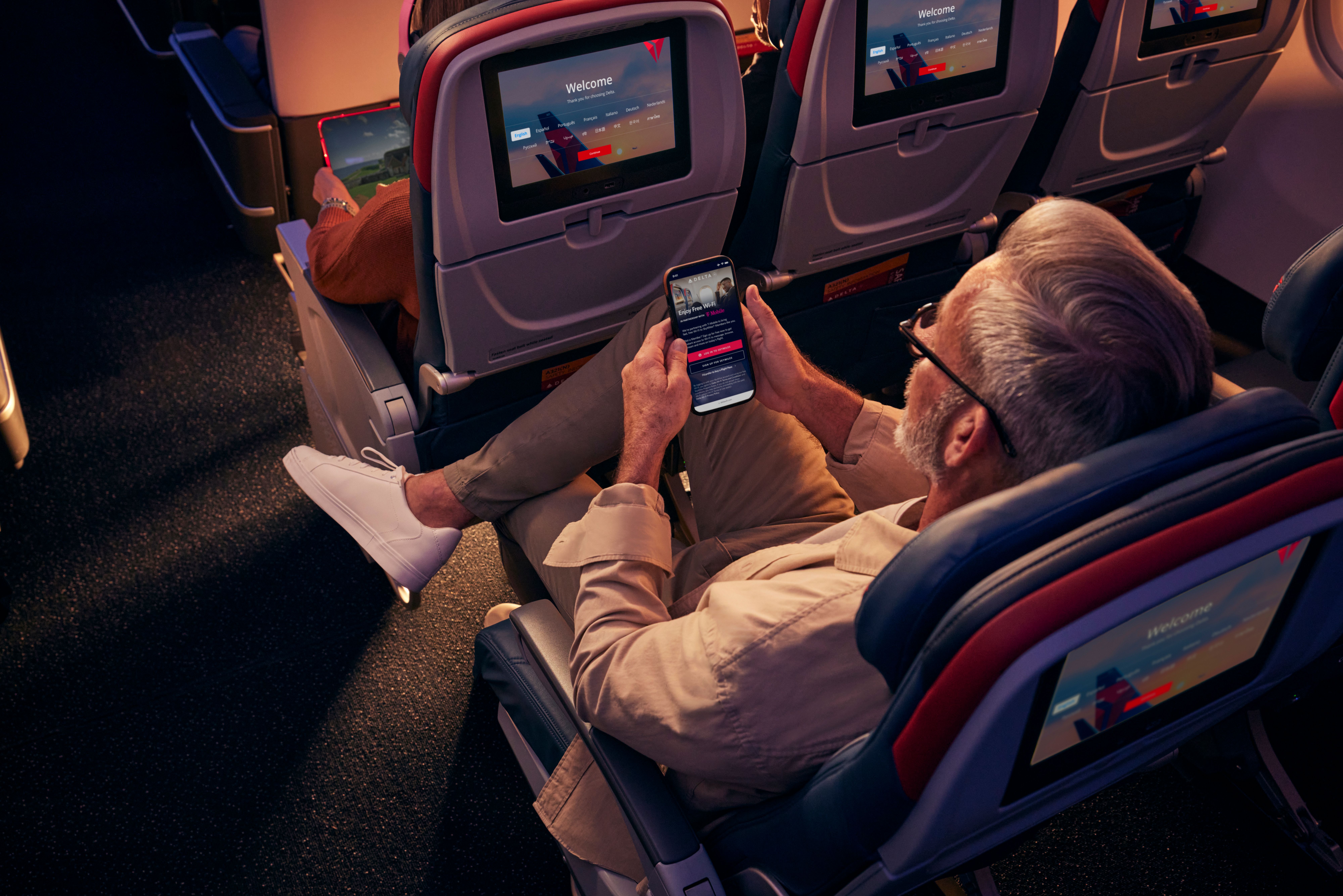 A passenger using his phone while sitting in Delta's Comfort Plus cabin.
