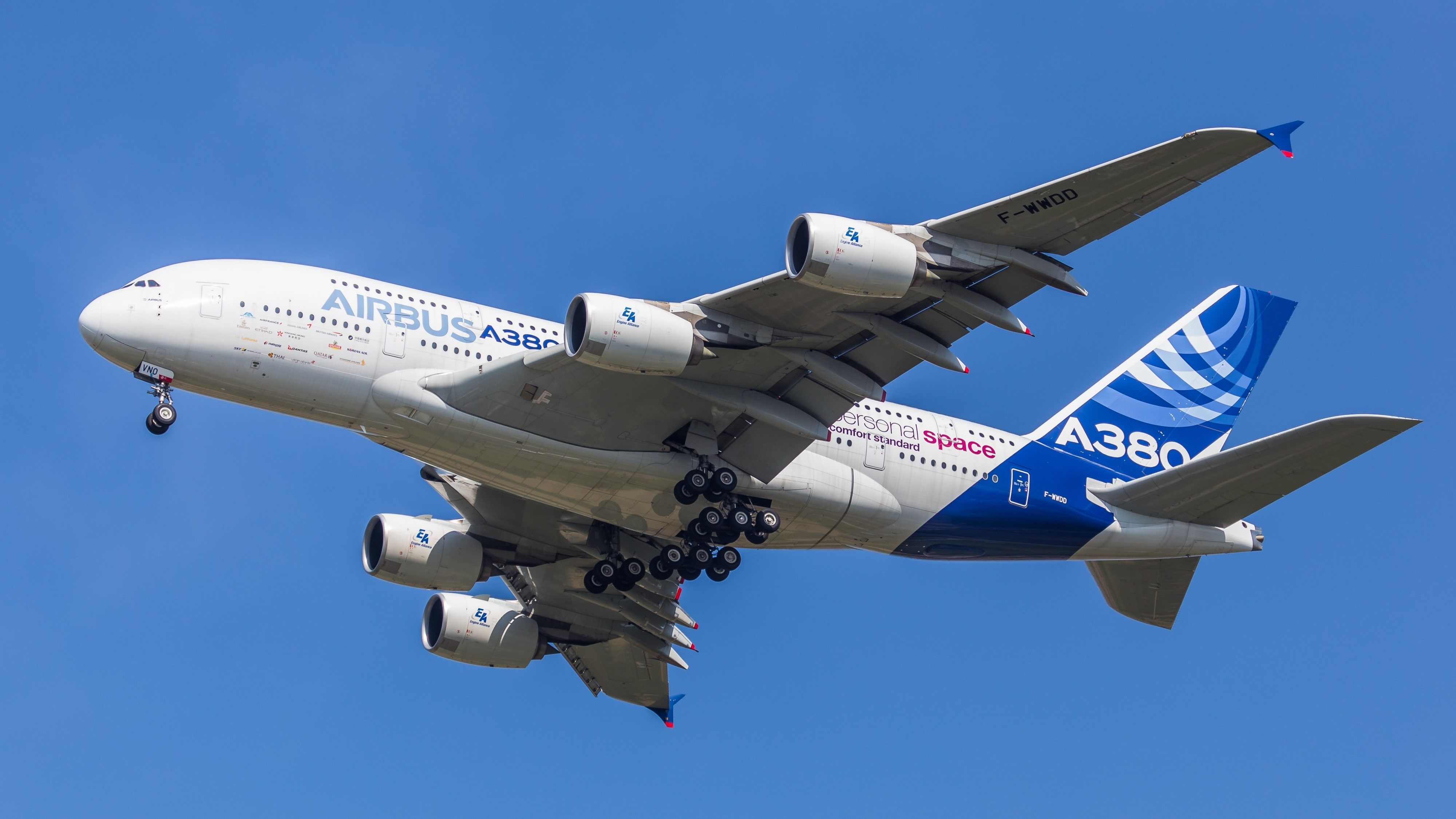 An Airbus A380 in house livery flying in the sky.