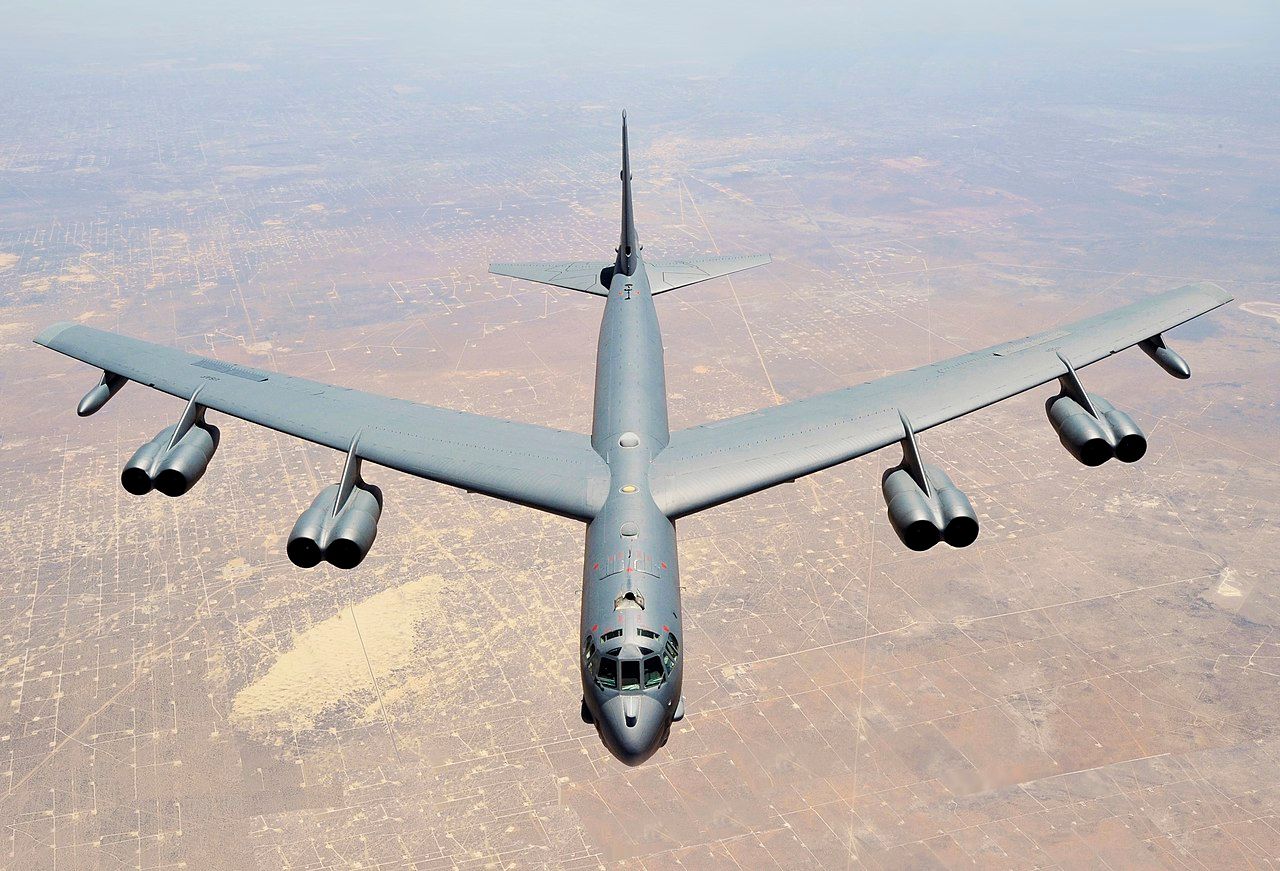 A B-52 Stratofortress flying over a desert area.