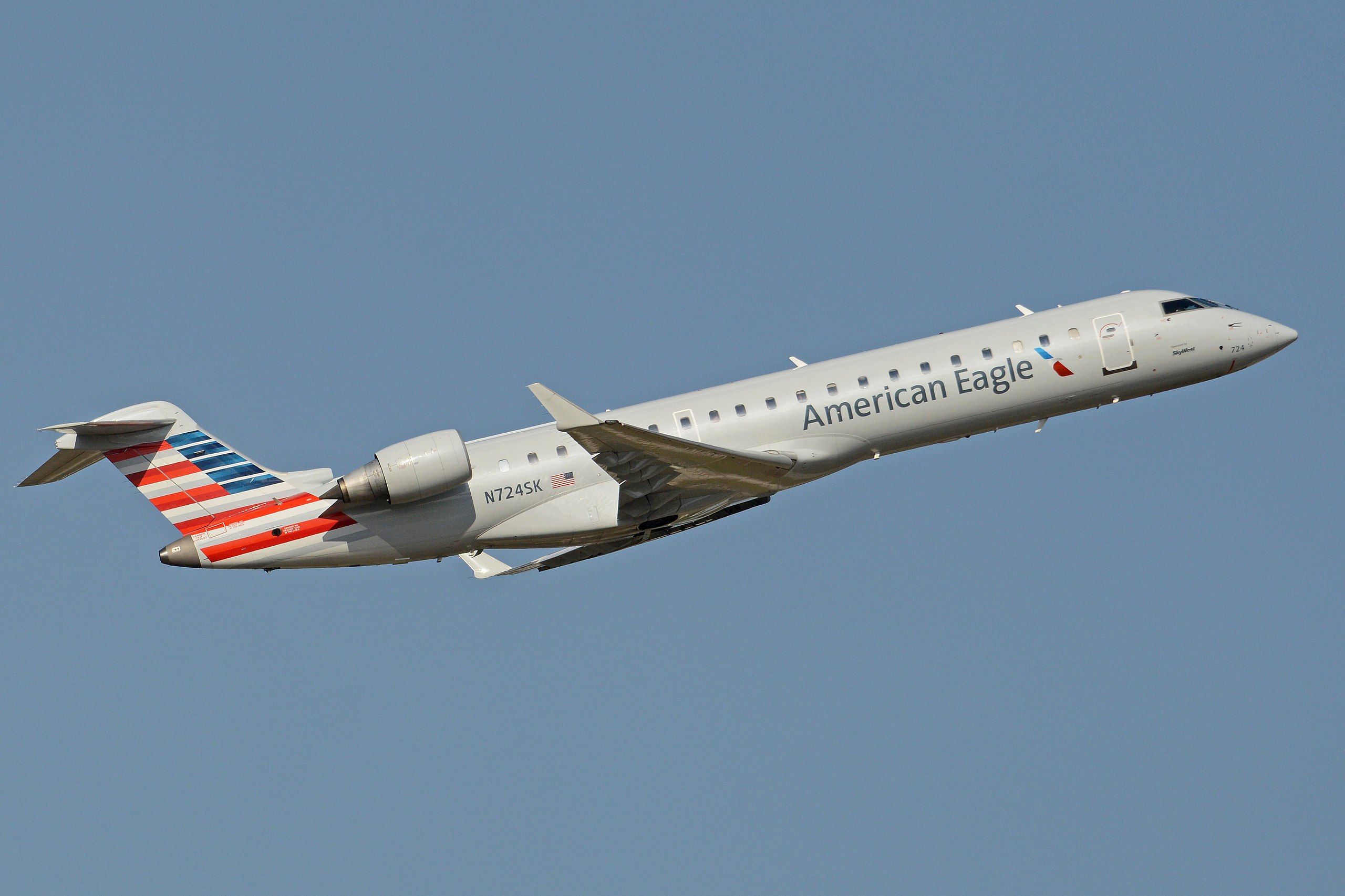 An American Eagle Bombardier CRJ-700 flying in the sky.