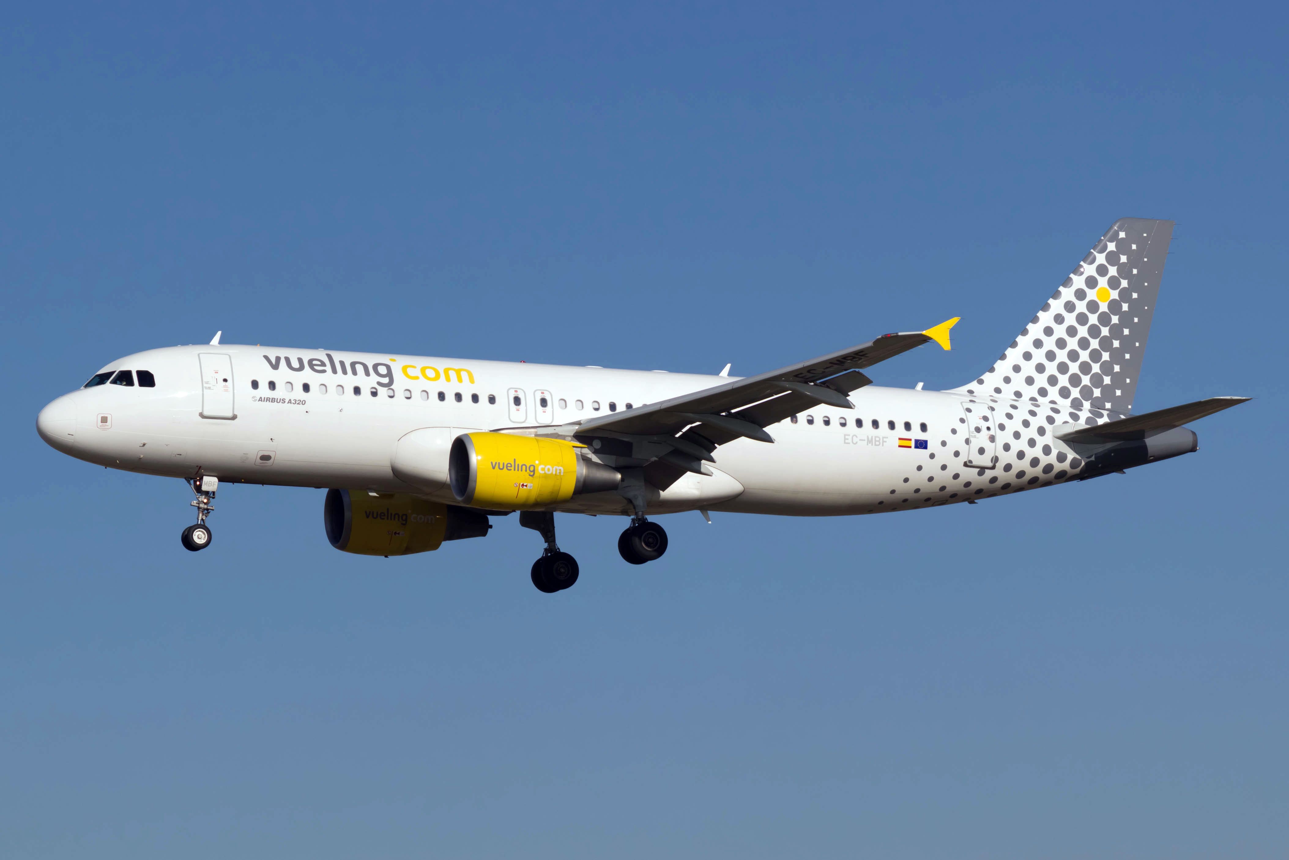 A Vueling Airbus A320 flying in the sky.
