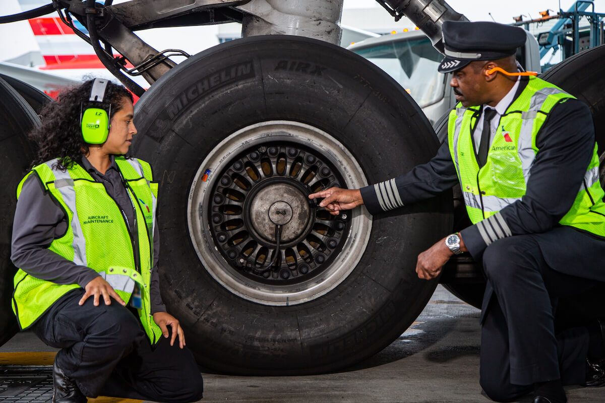 Two American Airlines employees inspecting an aircraft tire.