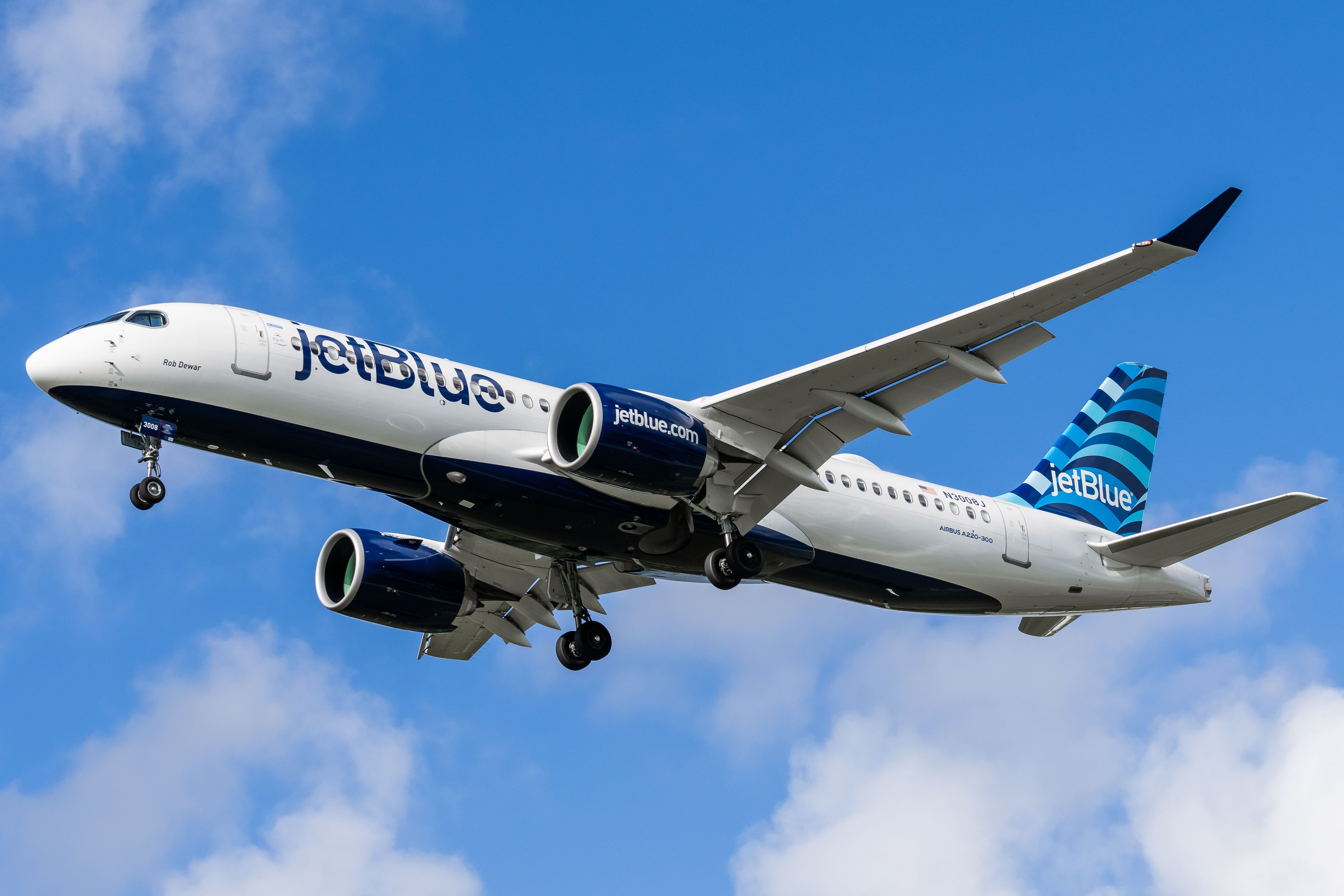 A JetBlue Airbus A220 flying in the sky.