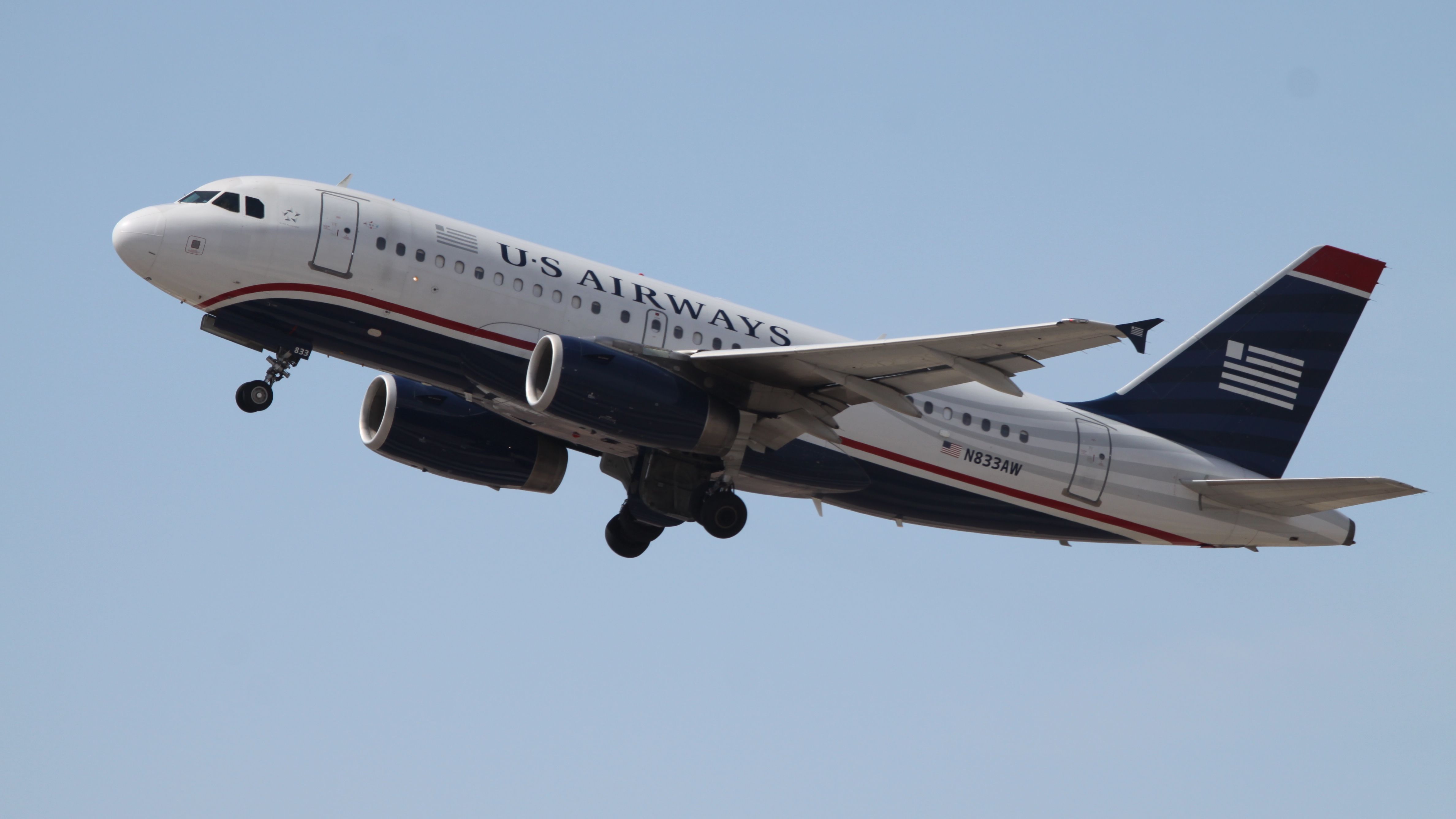 White Airbus passenger jetliner with US Airways livery flying in blue sky