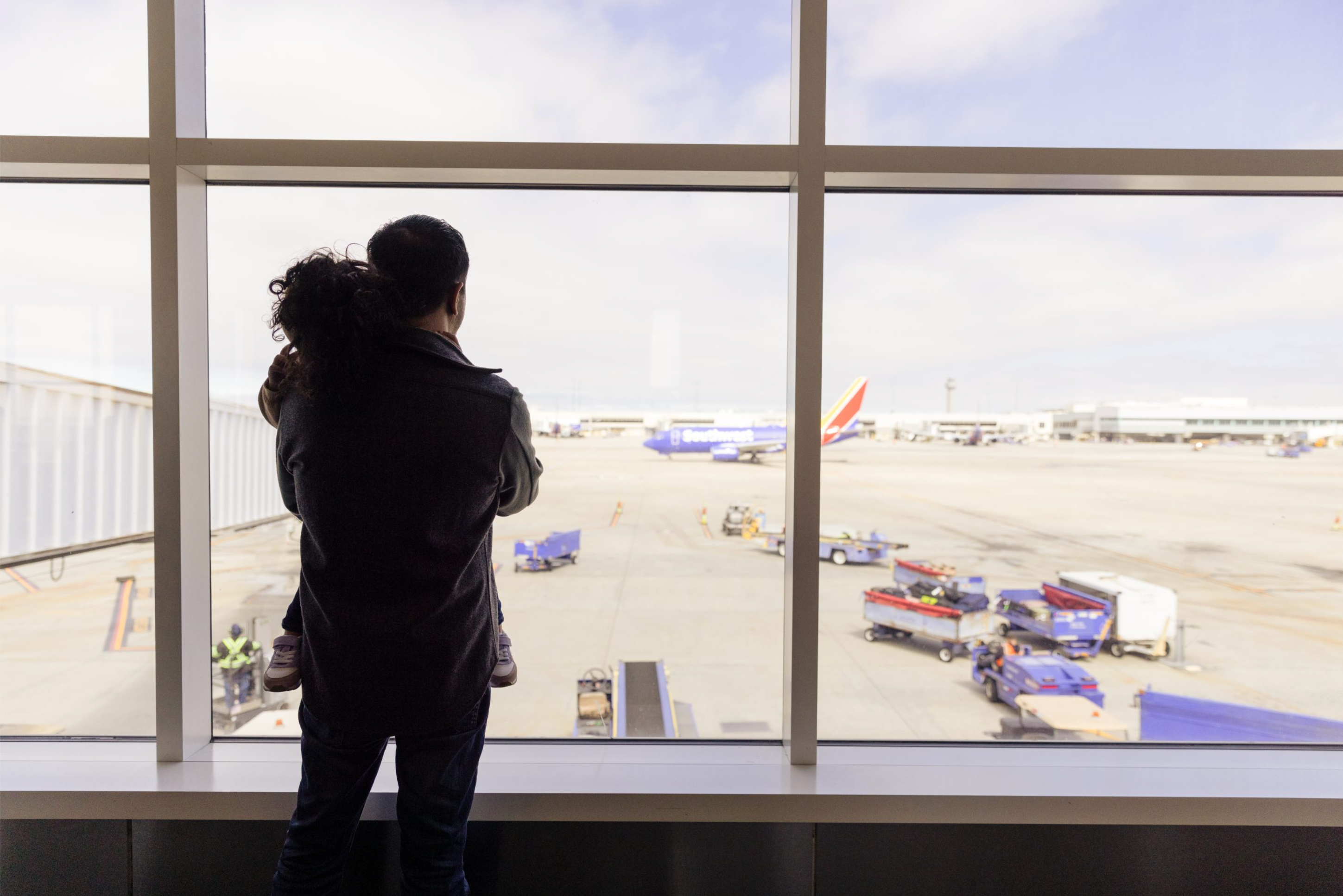 Passenger and child looking out over Oakland airport apron