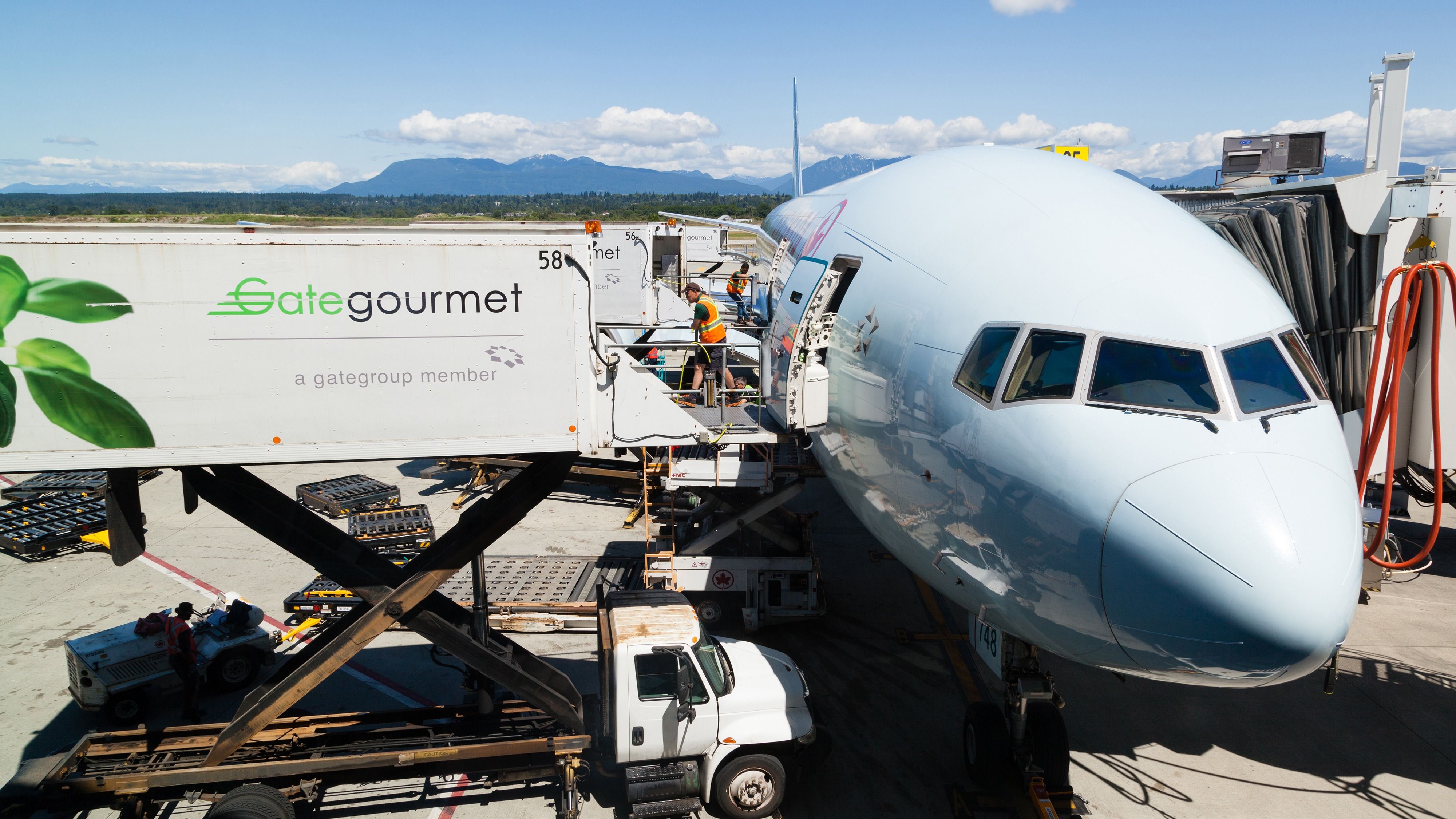 Ground staff prepares to load aircraft meals from a Gate Gourmet container onto an Air Canada 777.