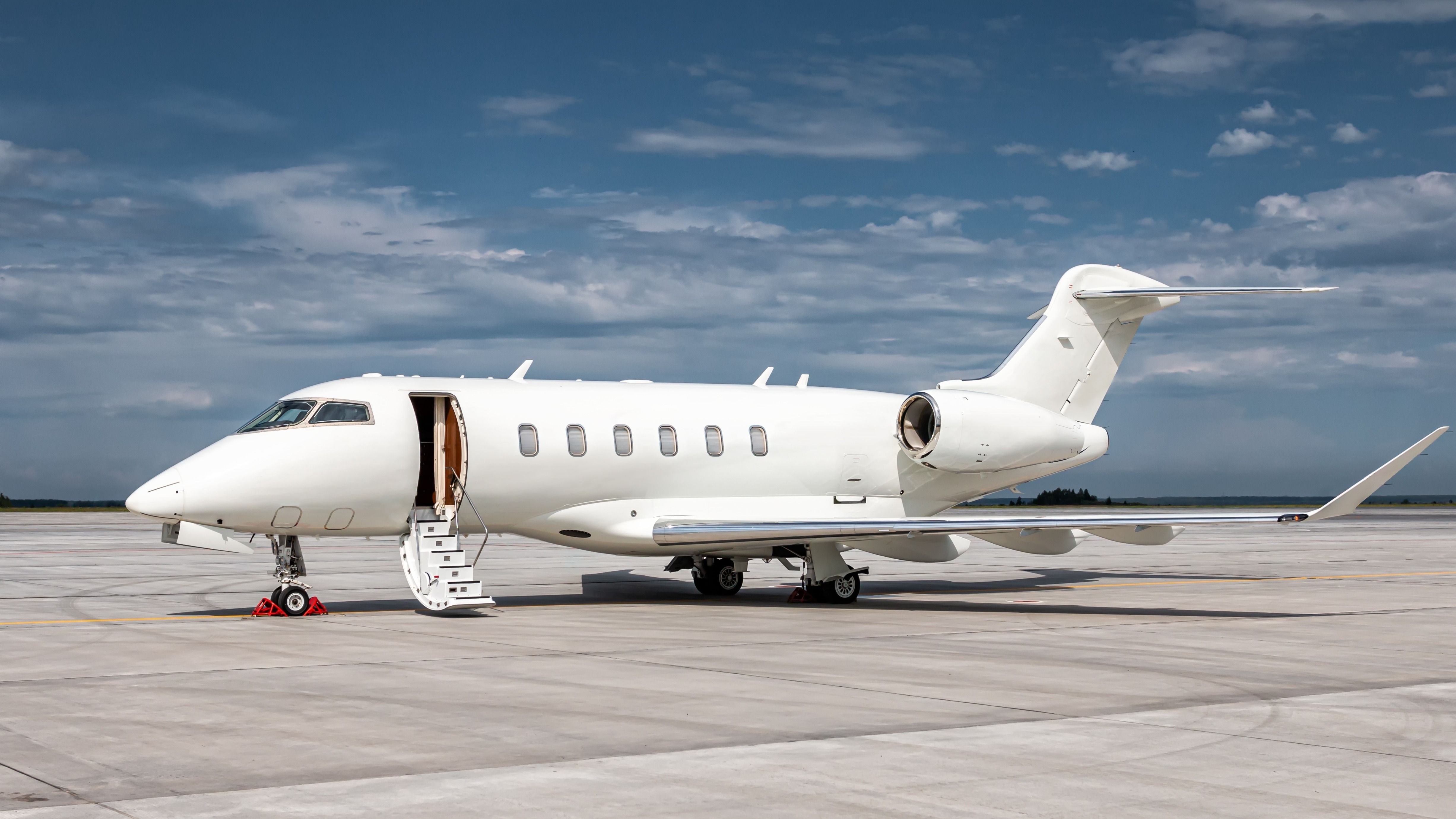 A white private jet parked at an airport.