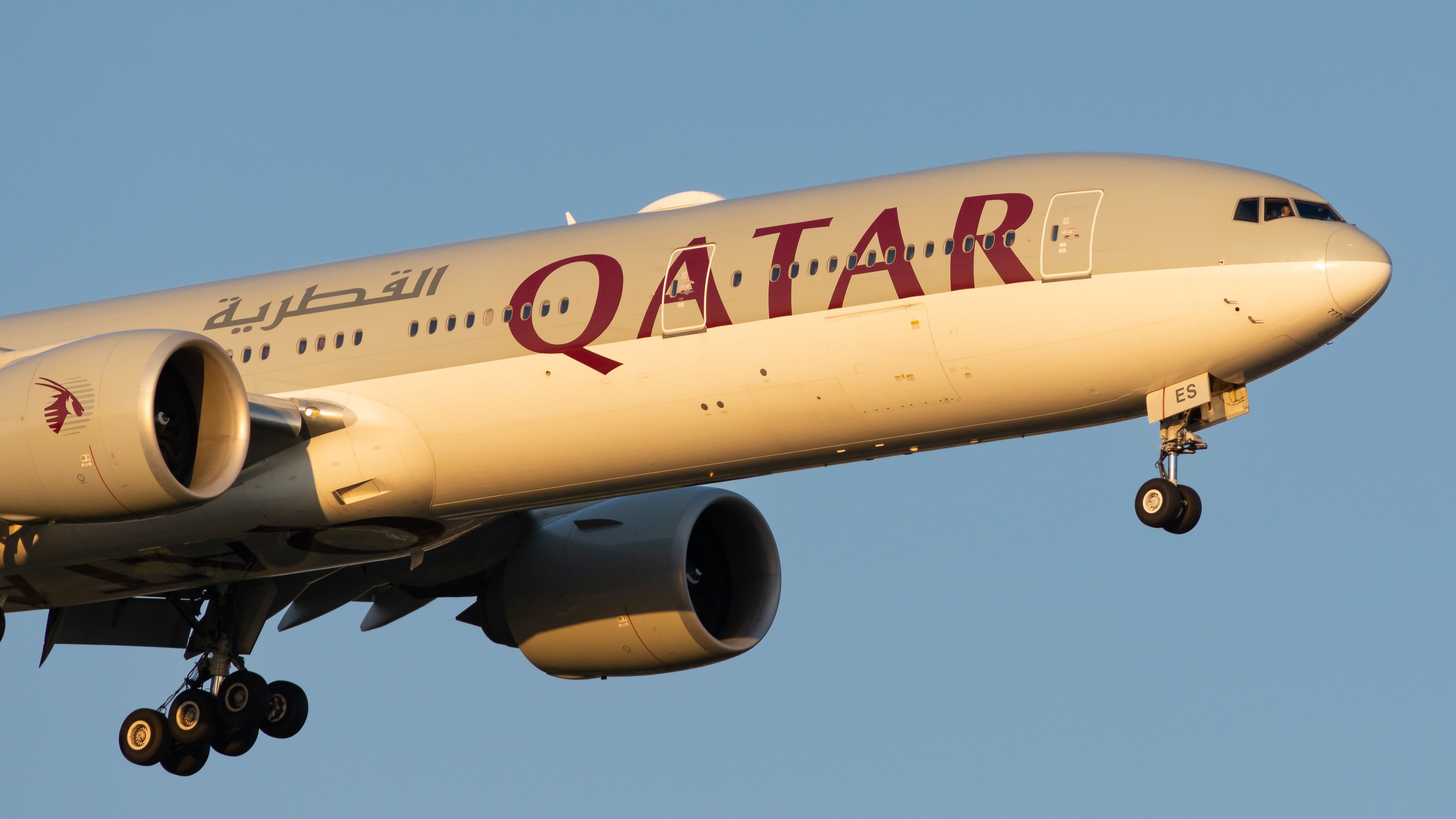 A Qatar Airways Boeing 777-300ER flying in the sky.