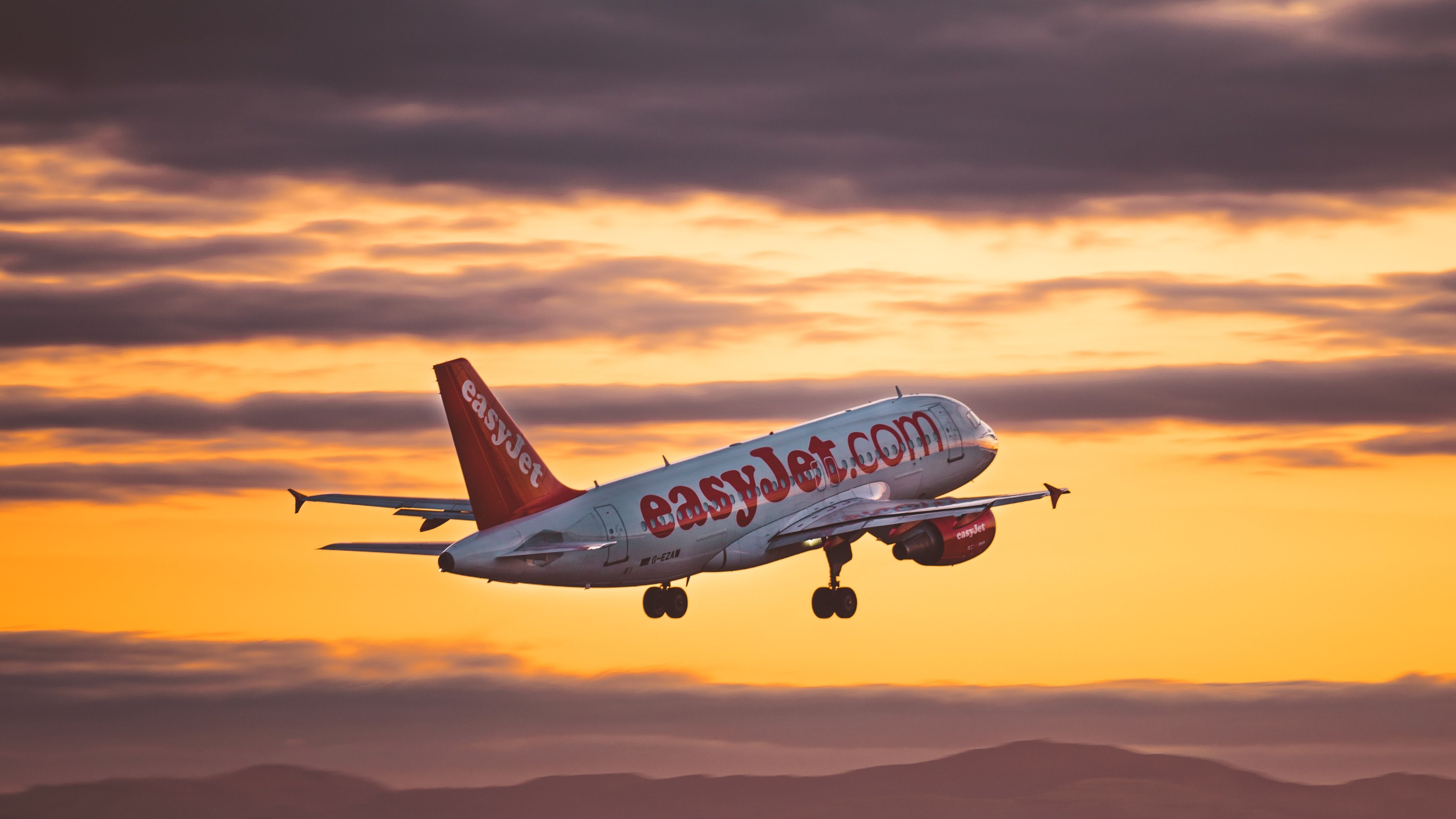 An easyJet Airbus A320 just after takeoff at sunset.