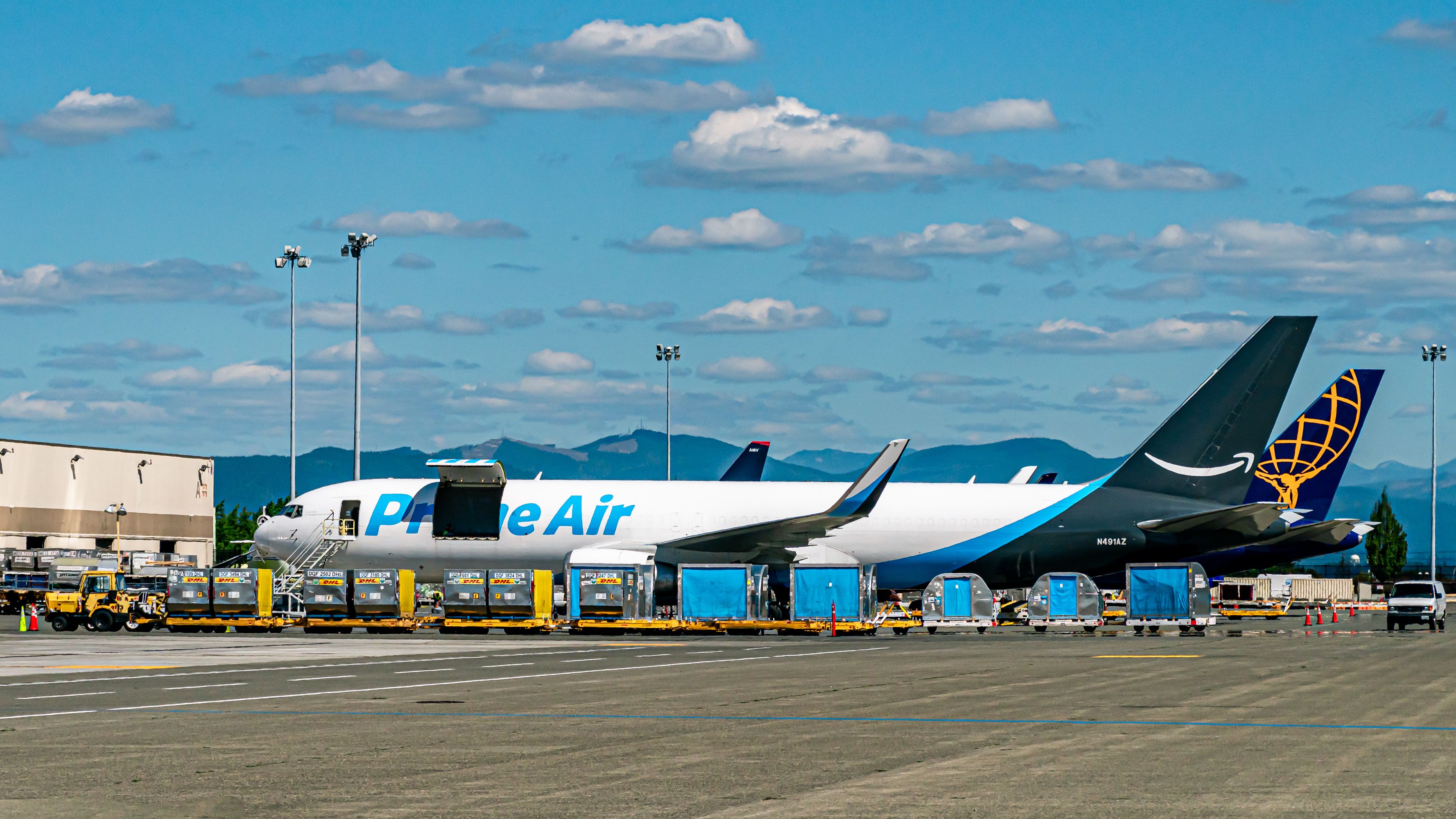 Busy SEA Air Cargo Ramp Under Blue Skies and Puffy Clouds