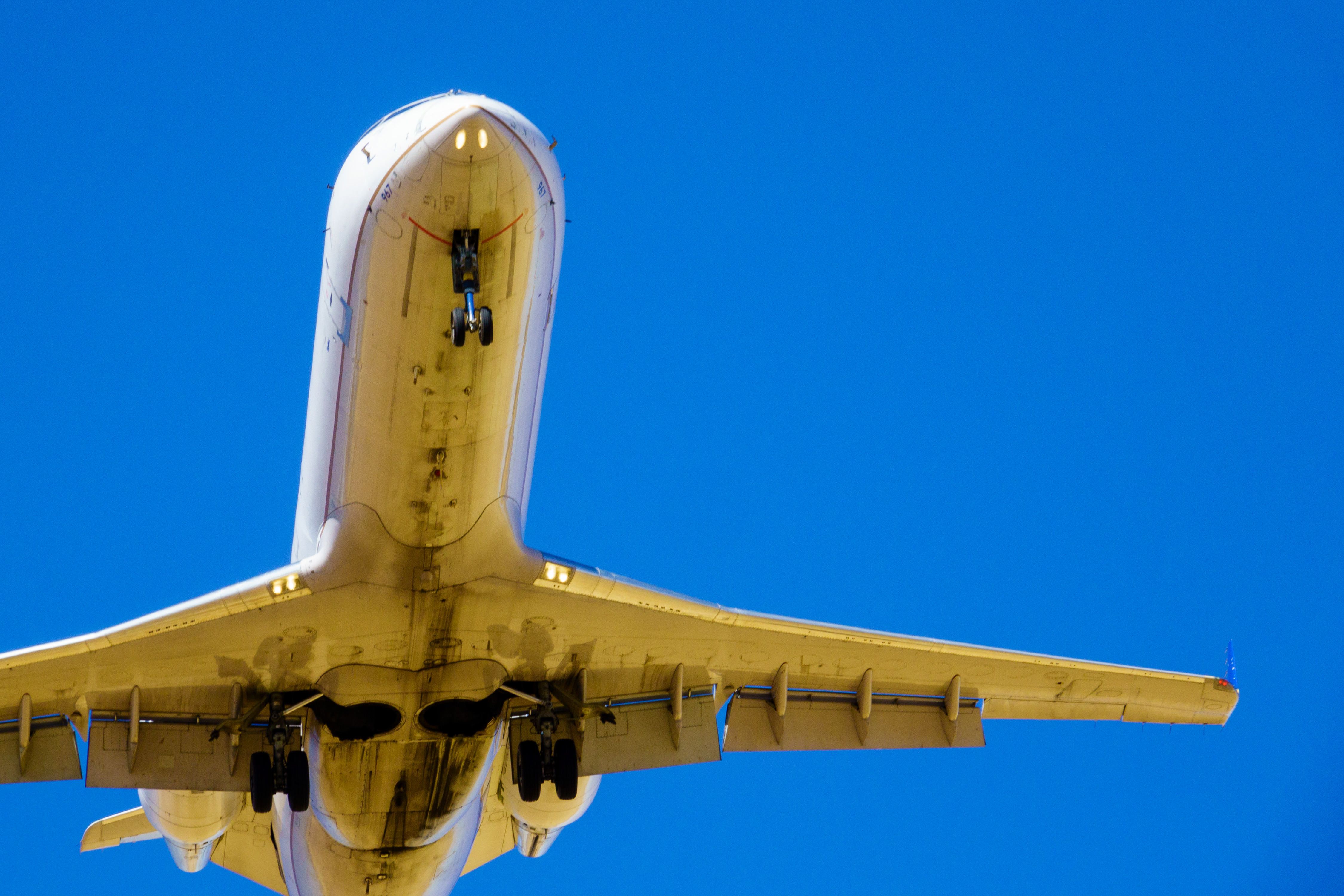 A closeup of an aircraft flying overhead with its gear down.