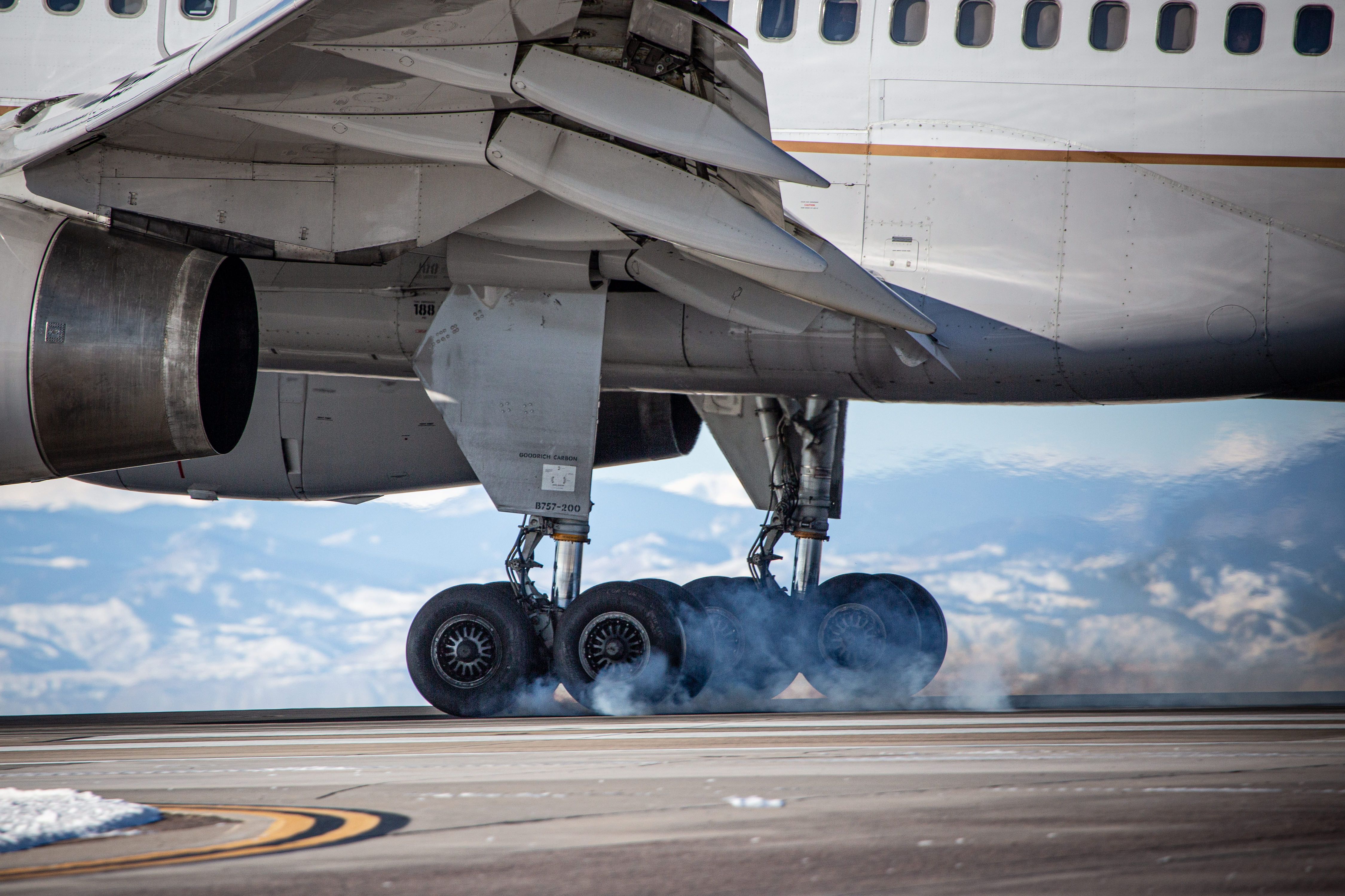 A closeup of an aicraft's landing gear making contact with the ground.