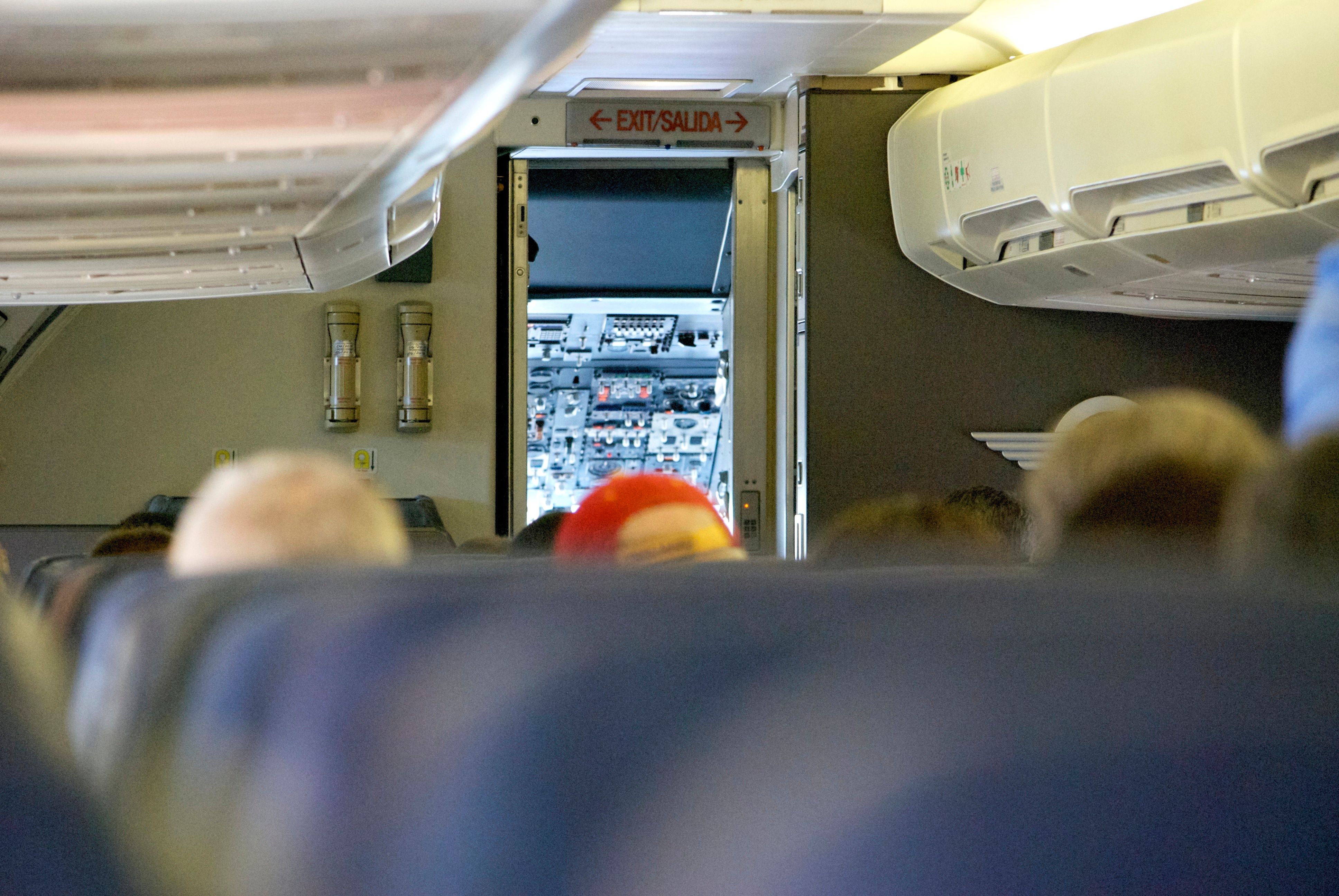 Inside an airliner cabin, looking at the open cockpit door.