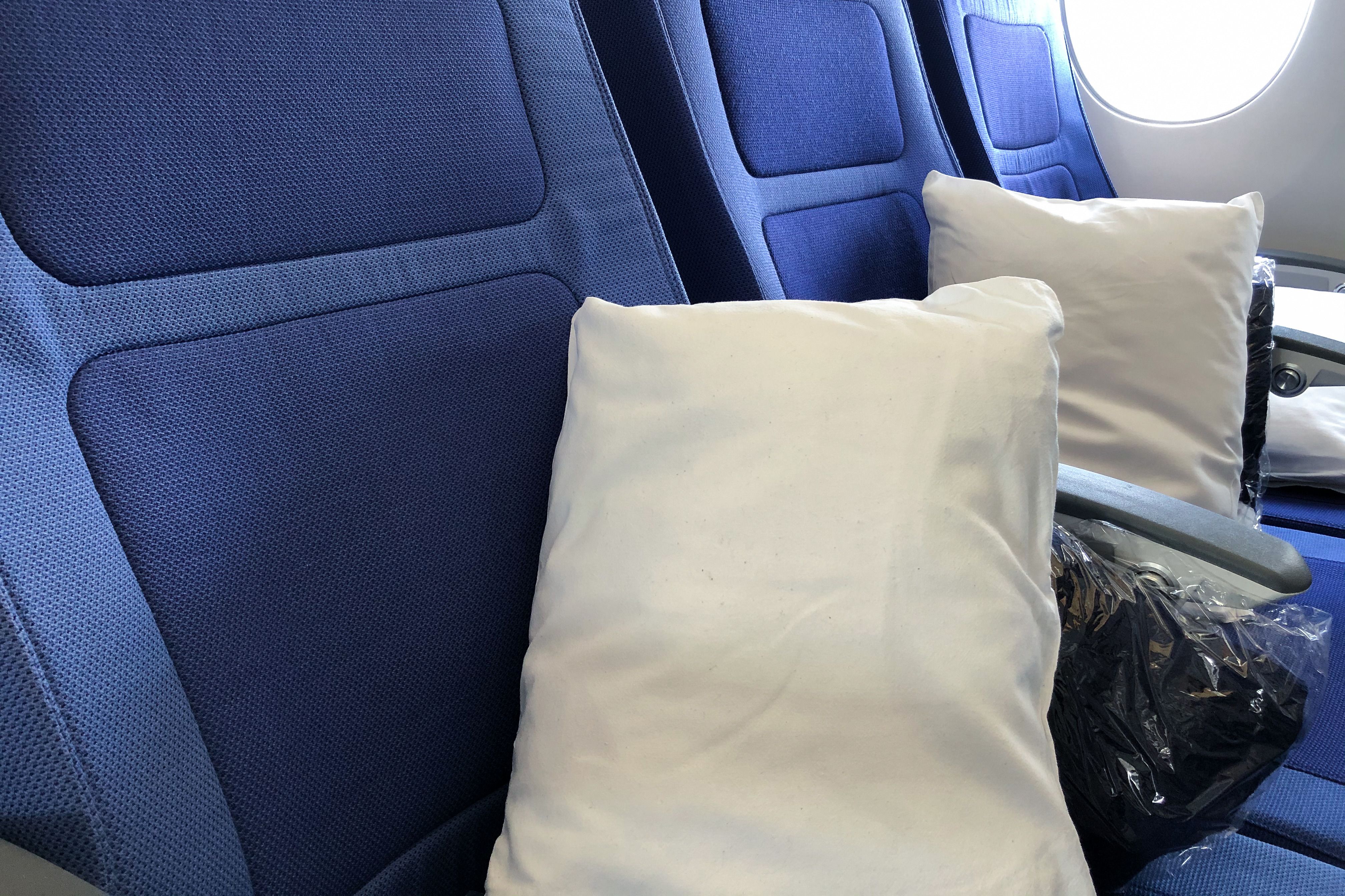 Wrapped blankets and pillows placed on a couple of aircraft seats.