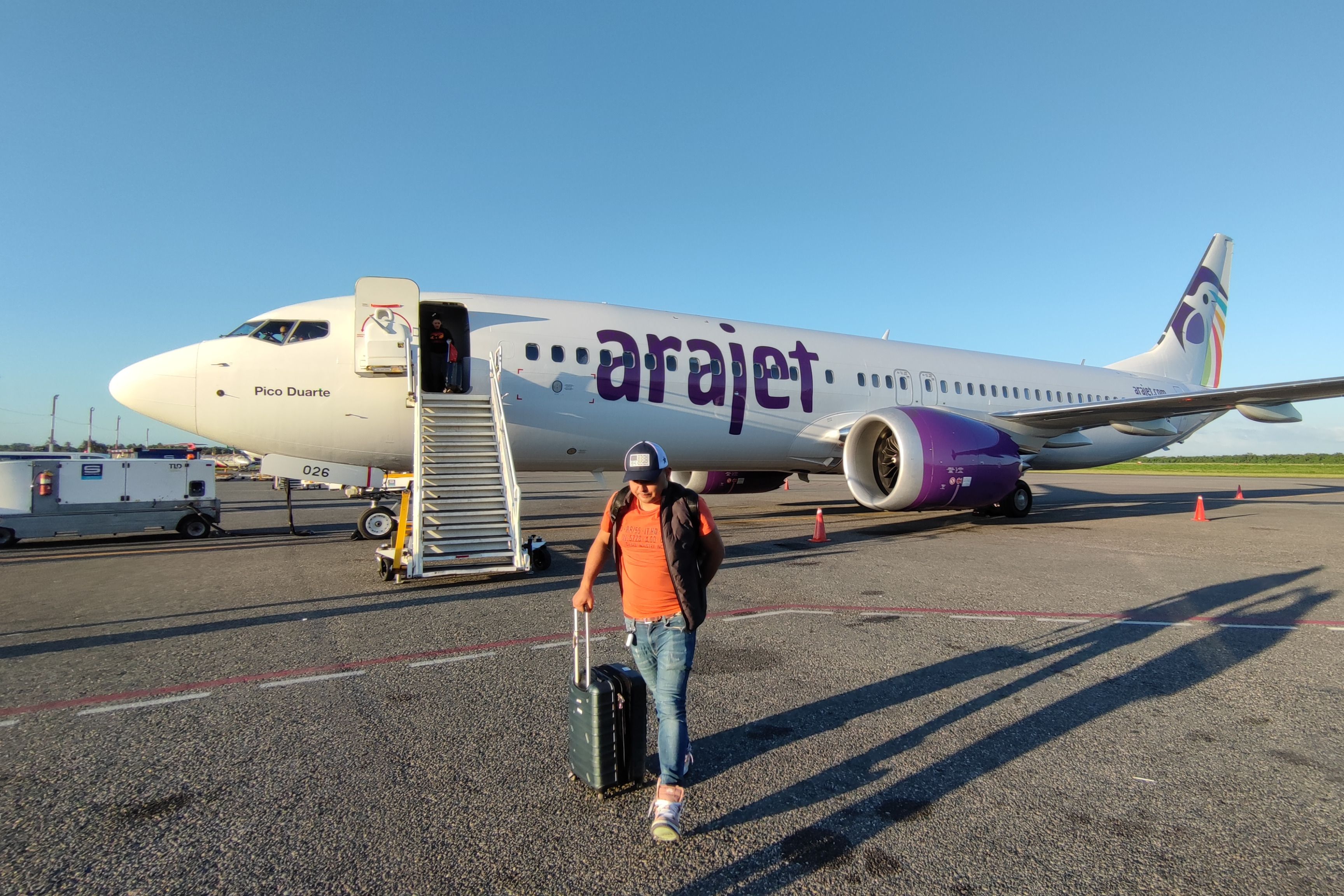A person walking in front of an Arajet Boeing 737 MAX aircraft