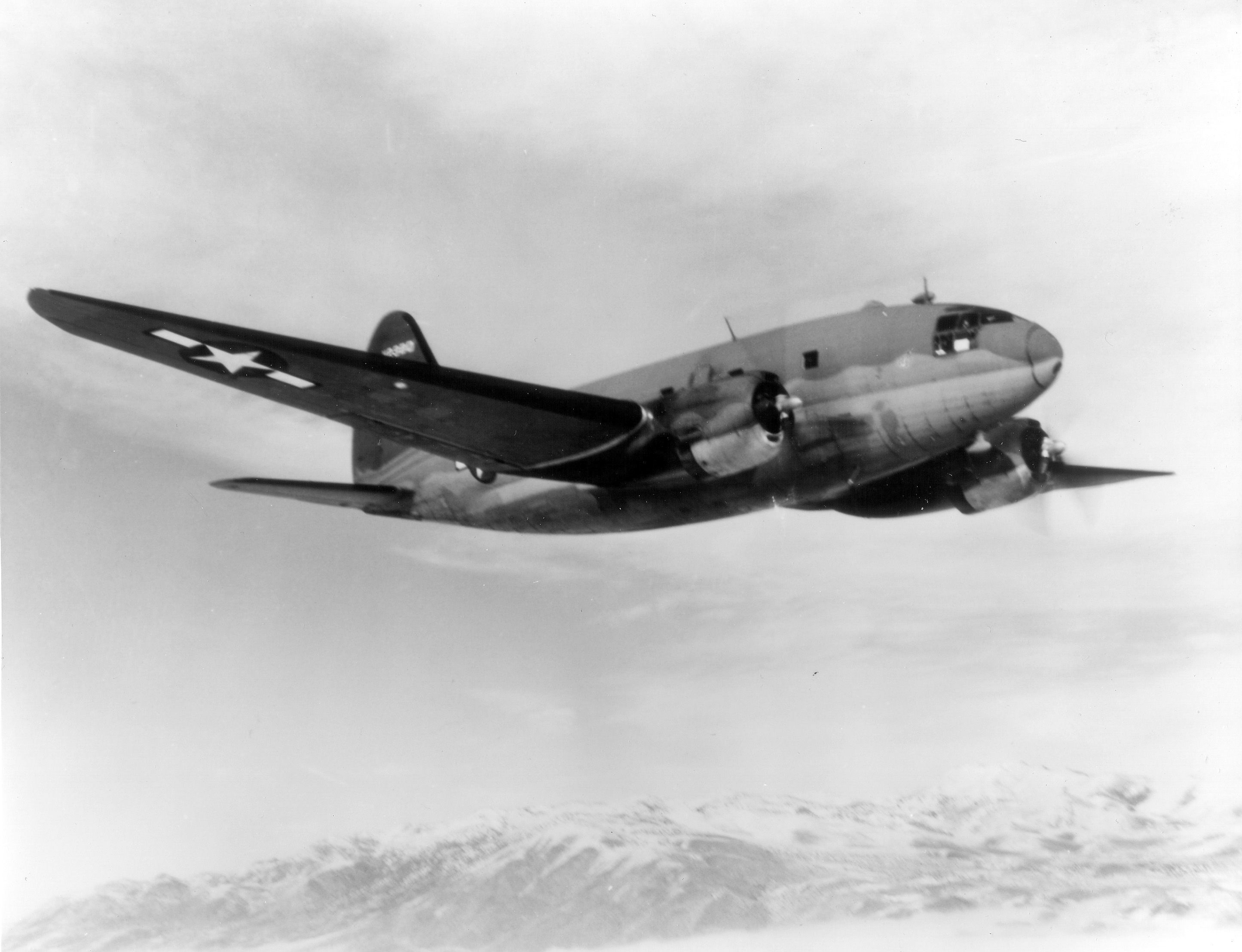 A black and white photo of a Curtiss-Wwright C-46 Commando in flight.