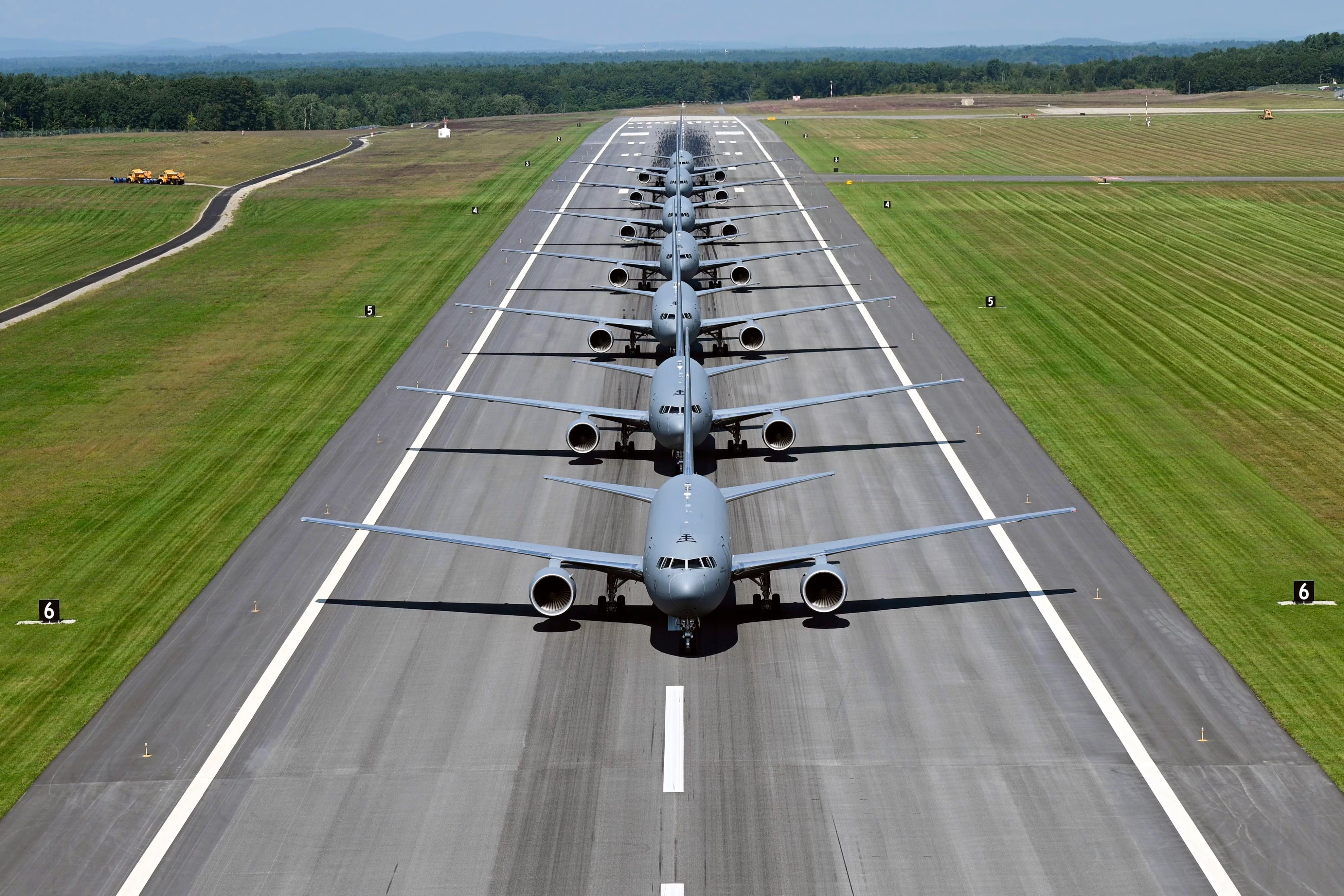 Severak Boeing KC-46 Tankers lined up on a runway.