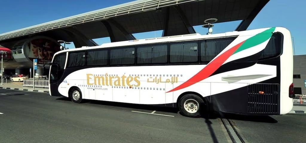 An Emirates airport shuttle bus at a bus stop.