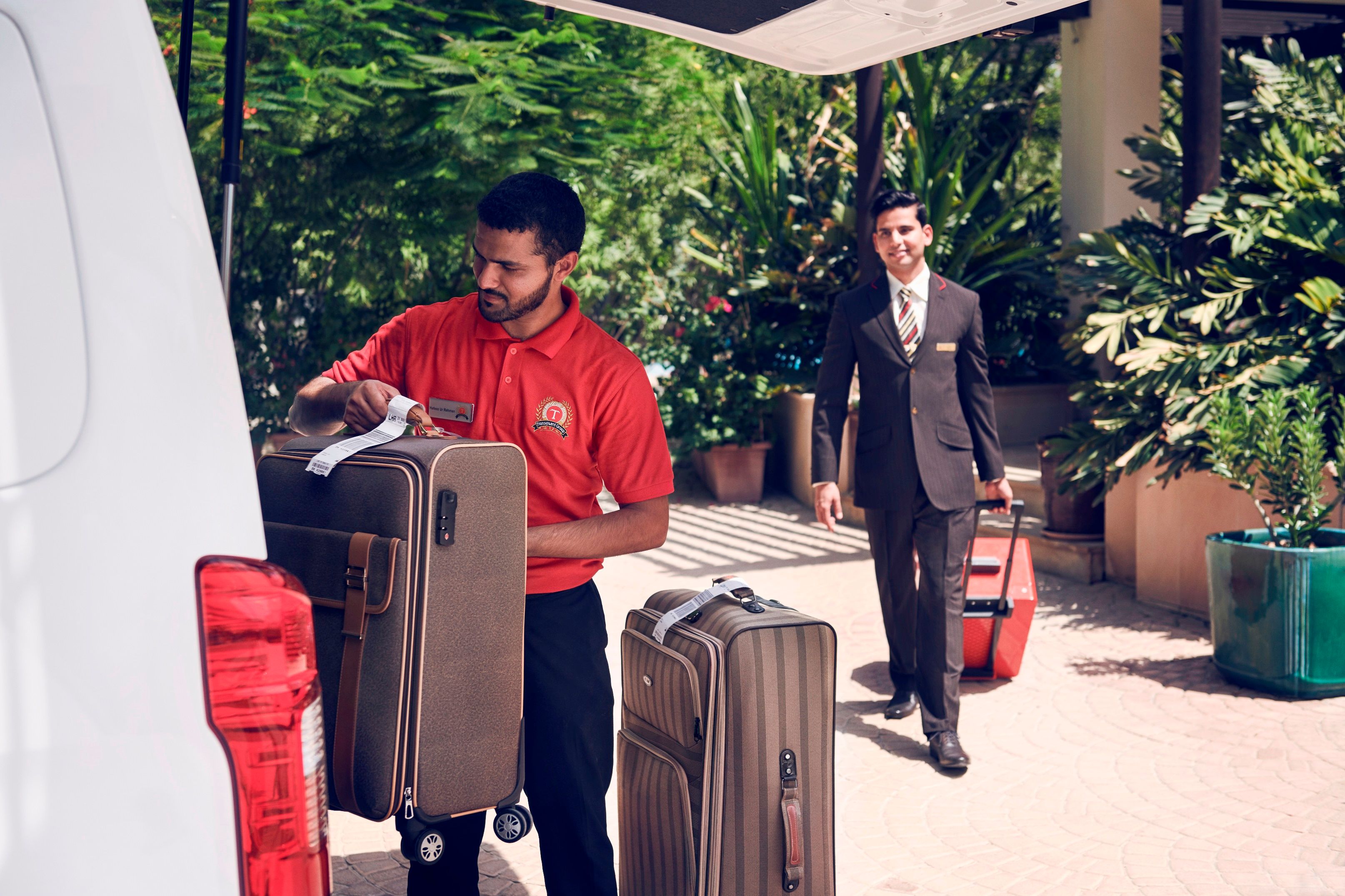 An Emirates worker loading suitcases into a van.