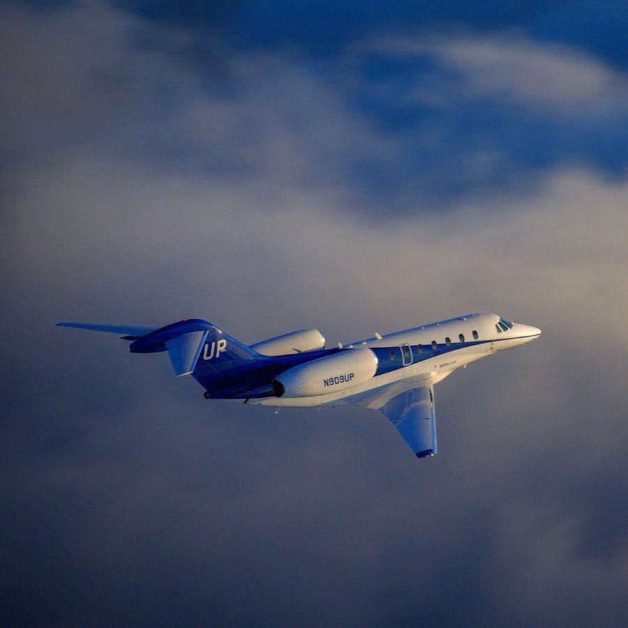 A Wheels Up jet flying above the clouds.