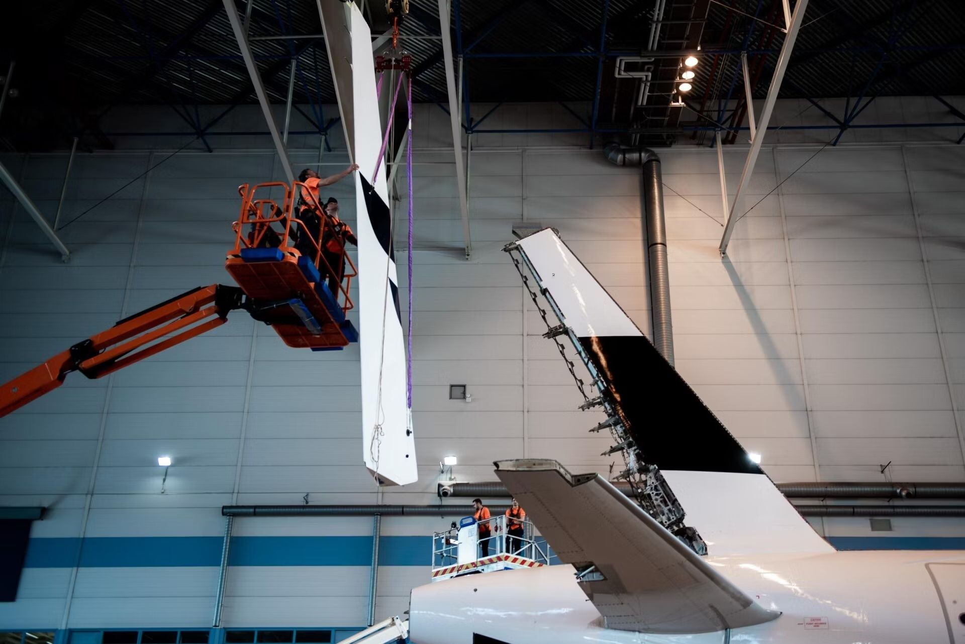 A team working on the rudder of a large Finnair aircraft.