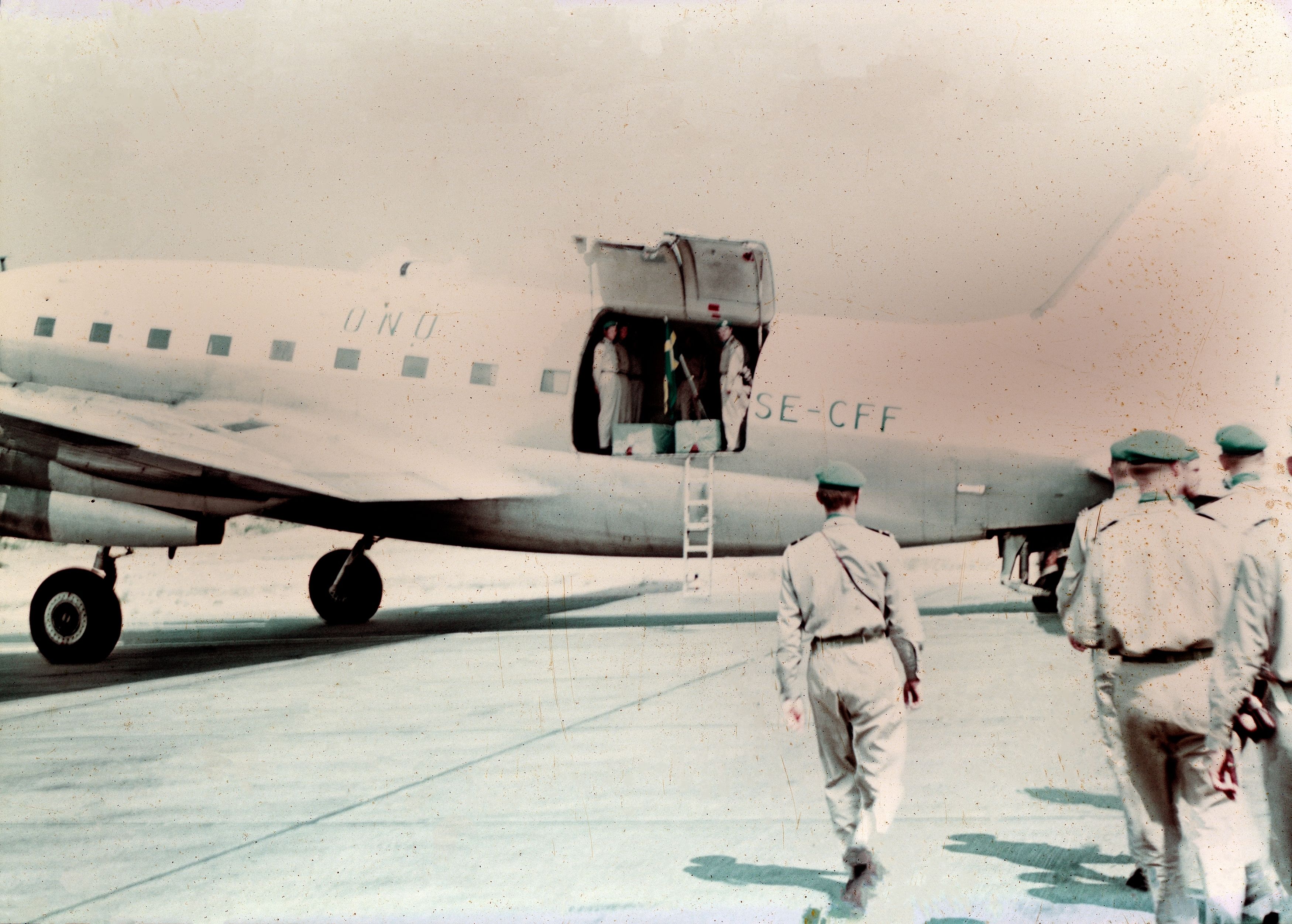 Servicemen walking near a parked Curtiss C-46 Commando aircraft.