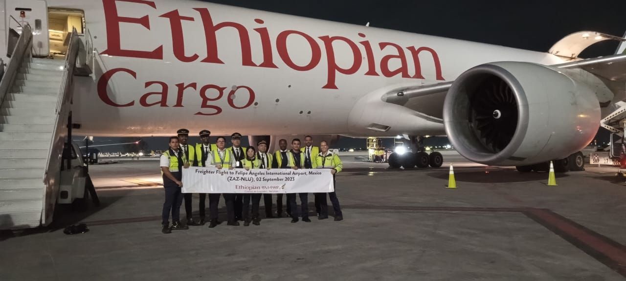 The crew of an Ethiopian Cargo flight holding a banner outside of a parked frieghter aircraft.