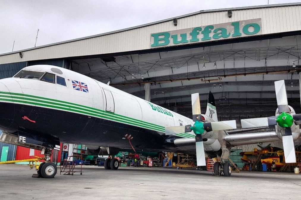 A Buffalo Airways Lockheed L-188 Electra parked halfway outside a hangar.