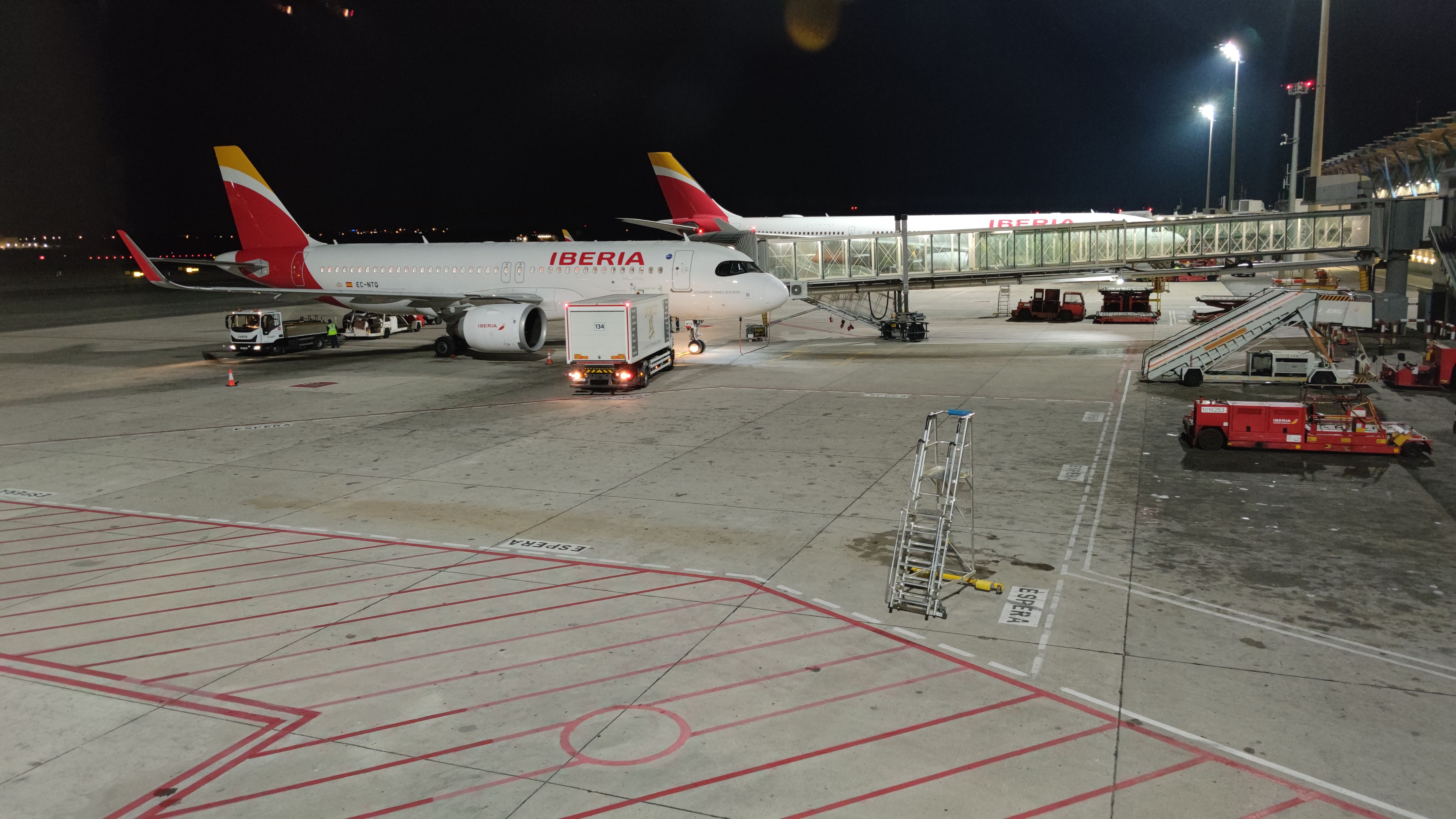 An Iberia aircraft parked at Madrid Barajas Airport at night.