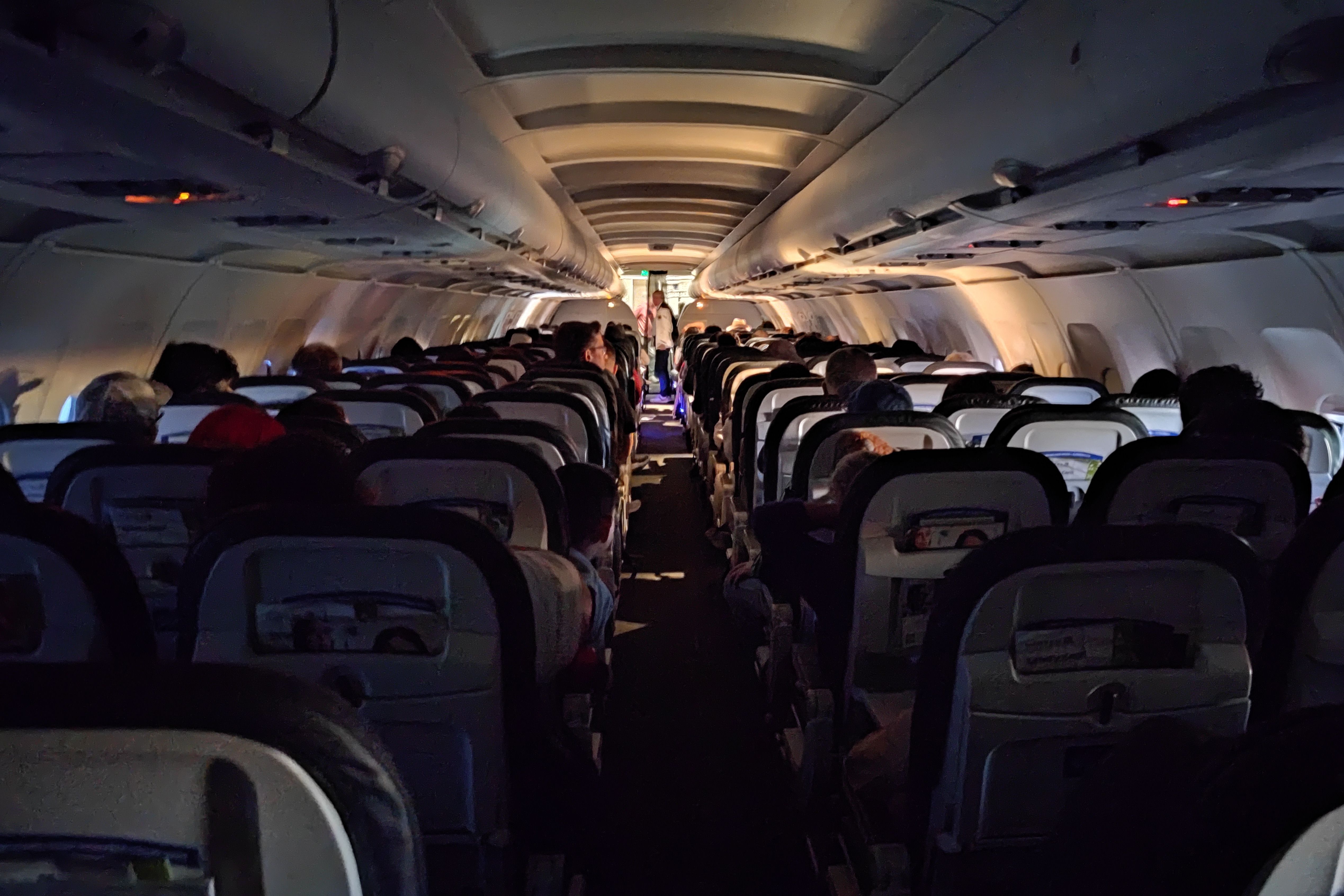 Onboard a United Airlines Airbus A319 aircraft cabin with the lights dimmed.