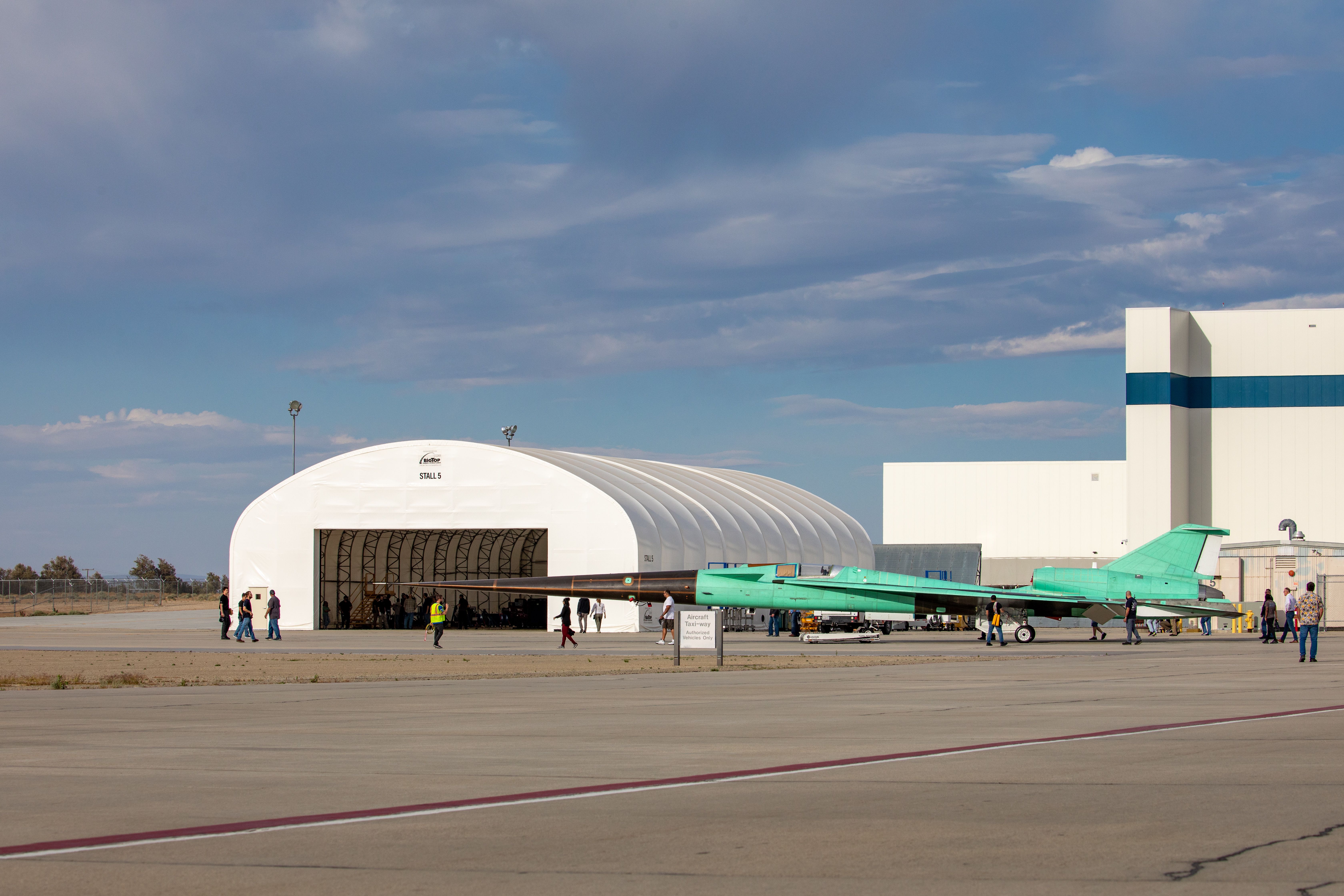 The X-59 parked outside of a hangar.