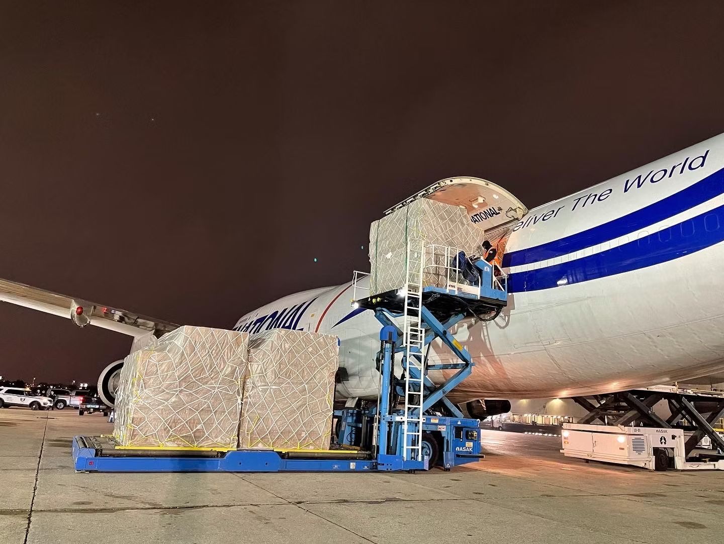 Workers load several large pallets of cargo onto a National Airlines Boeing 747 Freighter.