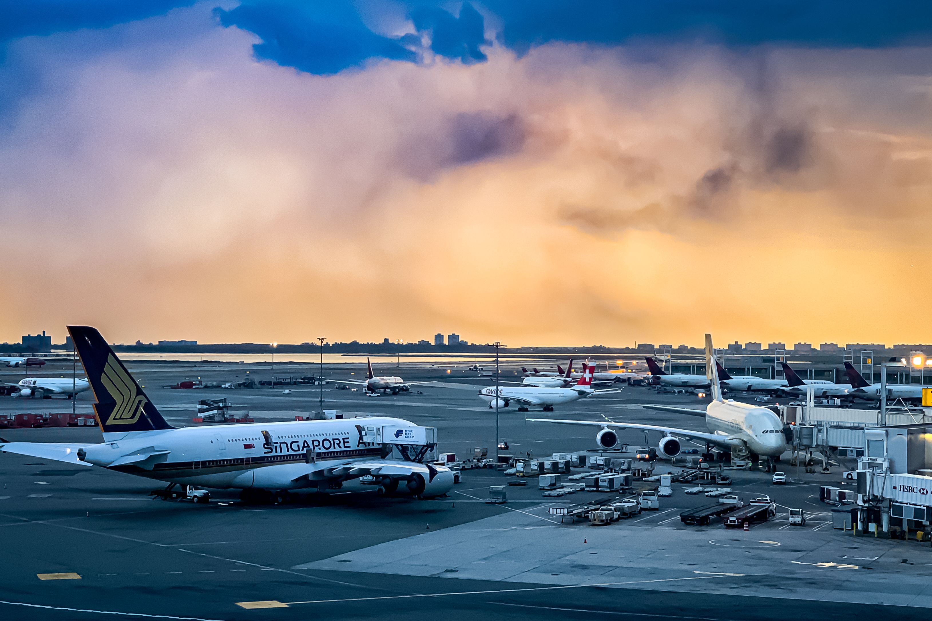 shutterstock_1527694265 - John F. Kennedy International Airport (JFK Airport) and the airplanes on the ground during a rainy thunderstorm clouds over the sunset. Queens, New York, USA, October 2, 2019.