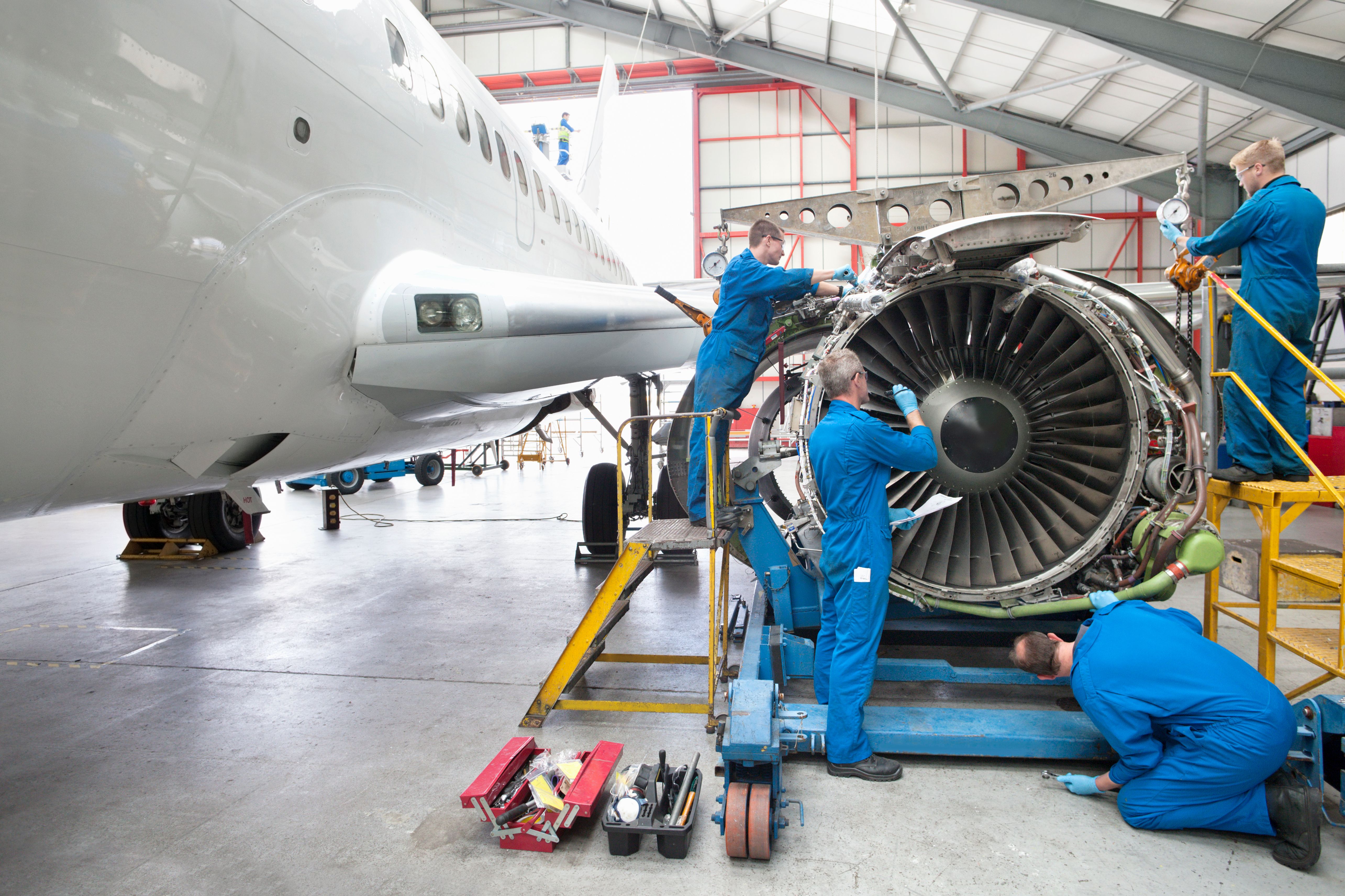 Several maintenance workers inspecting a jet engine.