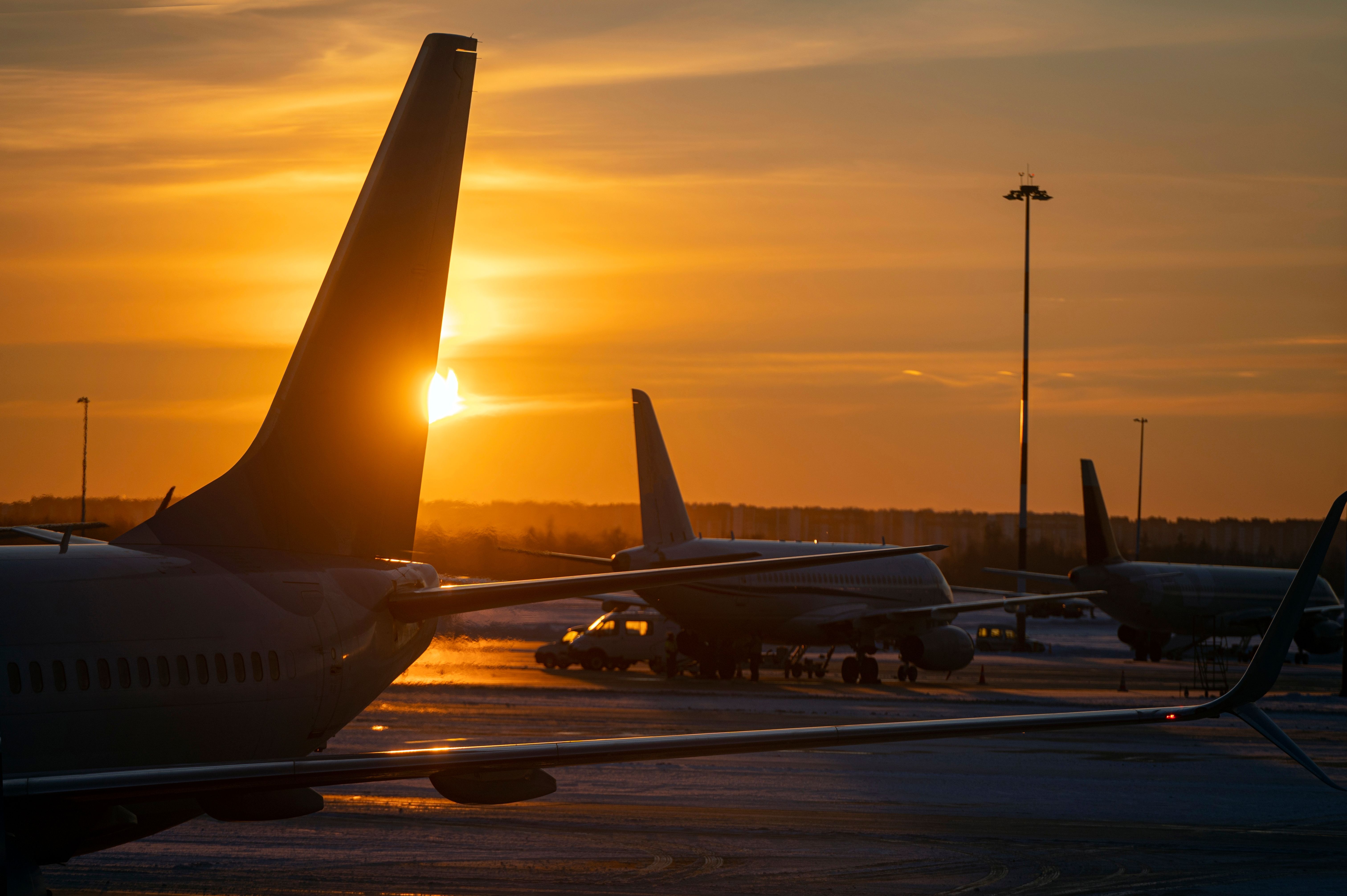 Silhouettes of the airplanes with Tails at airport during bright yellow sunset, concept picture about transport as background