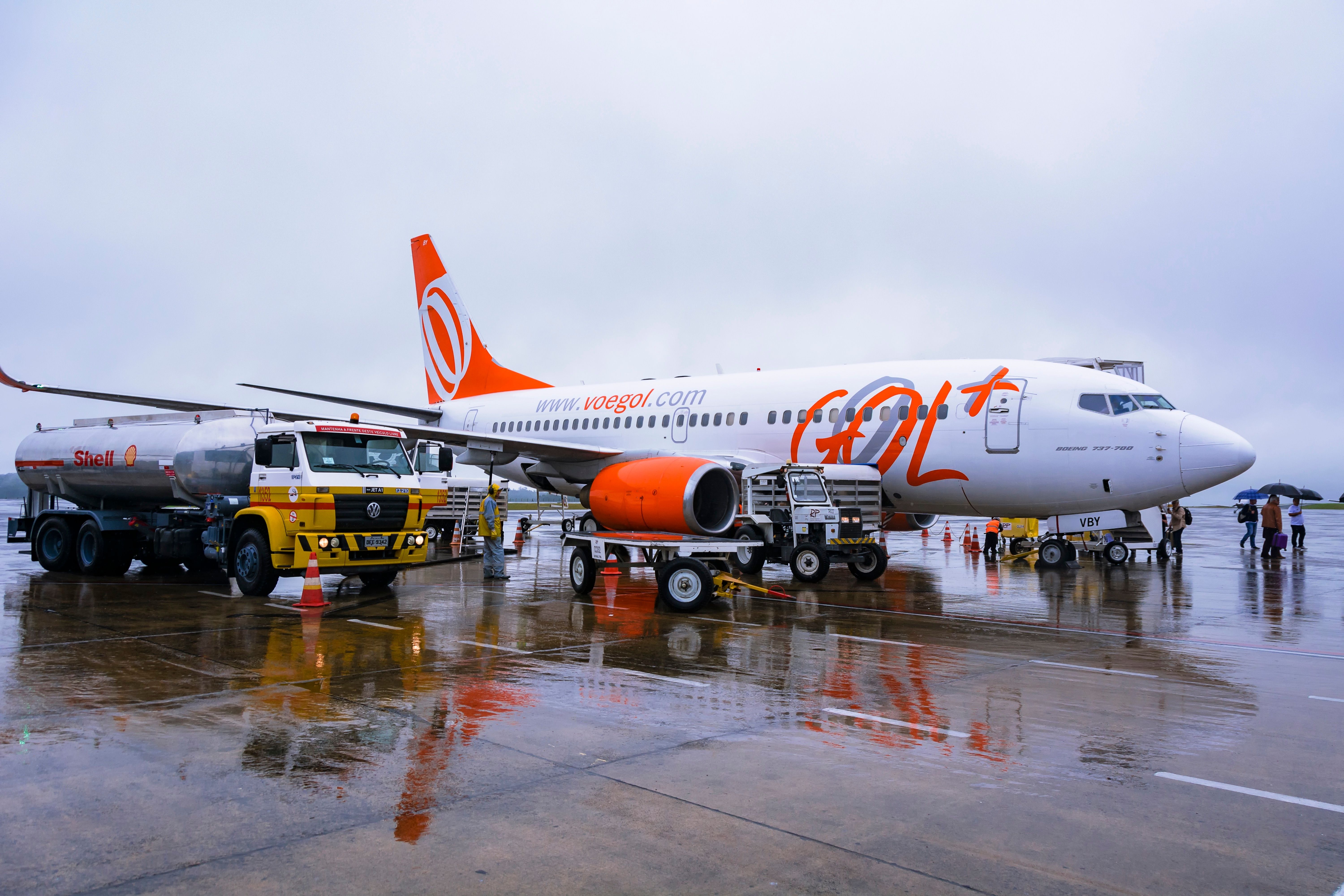 A GOL Boeing 737 parked at an airport with A Refueling Truck nearby.