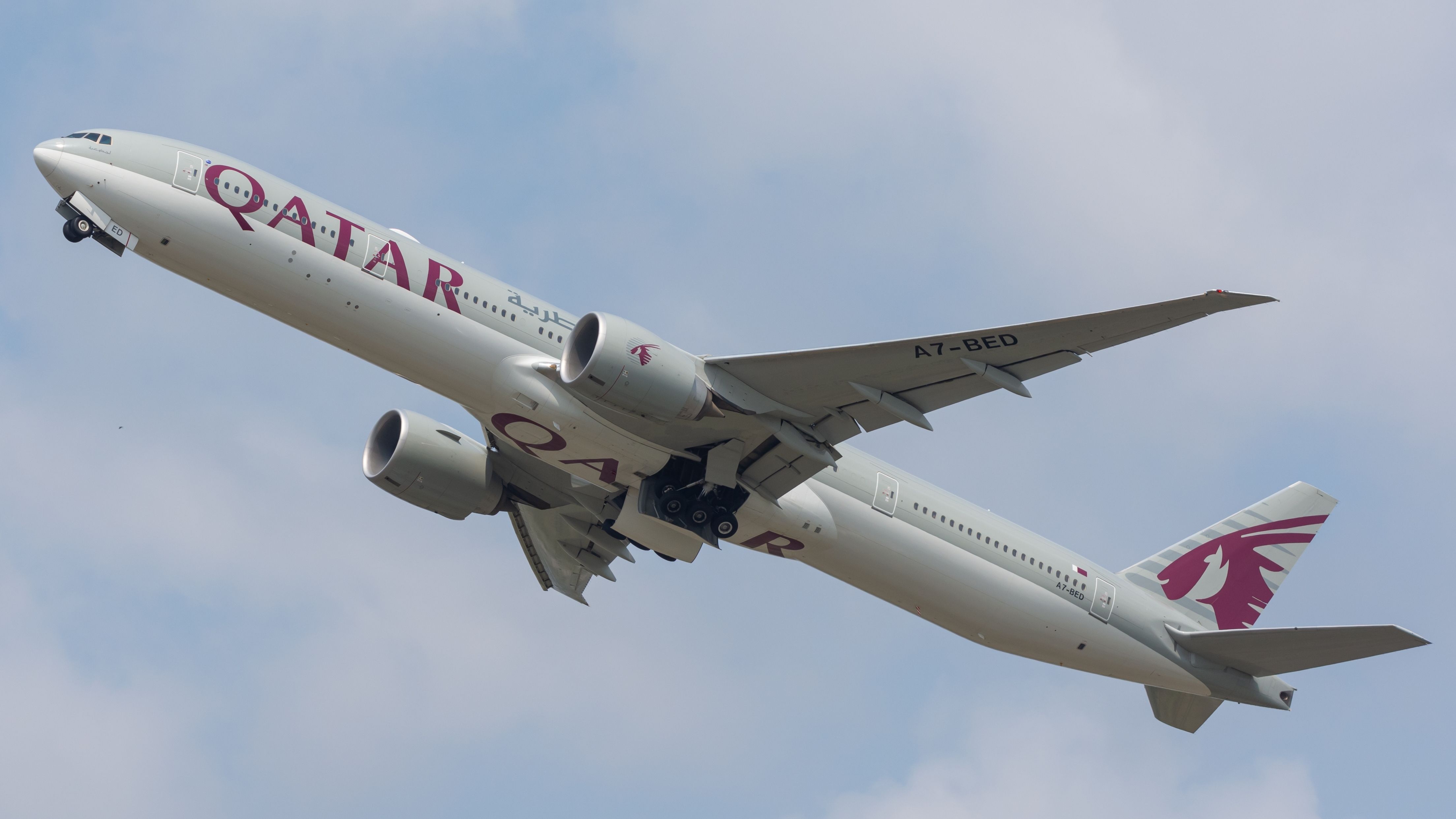 A Qatar Airways Boeing 777 flying in the sky.